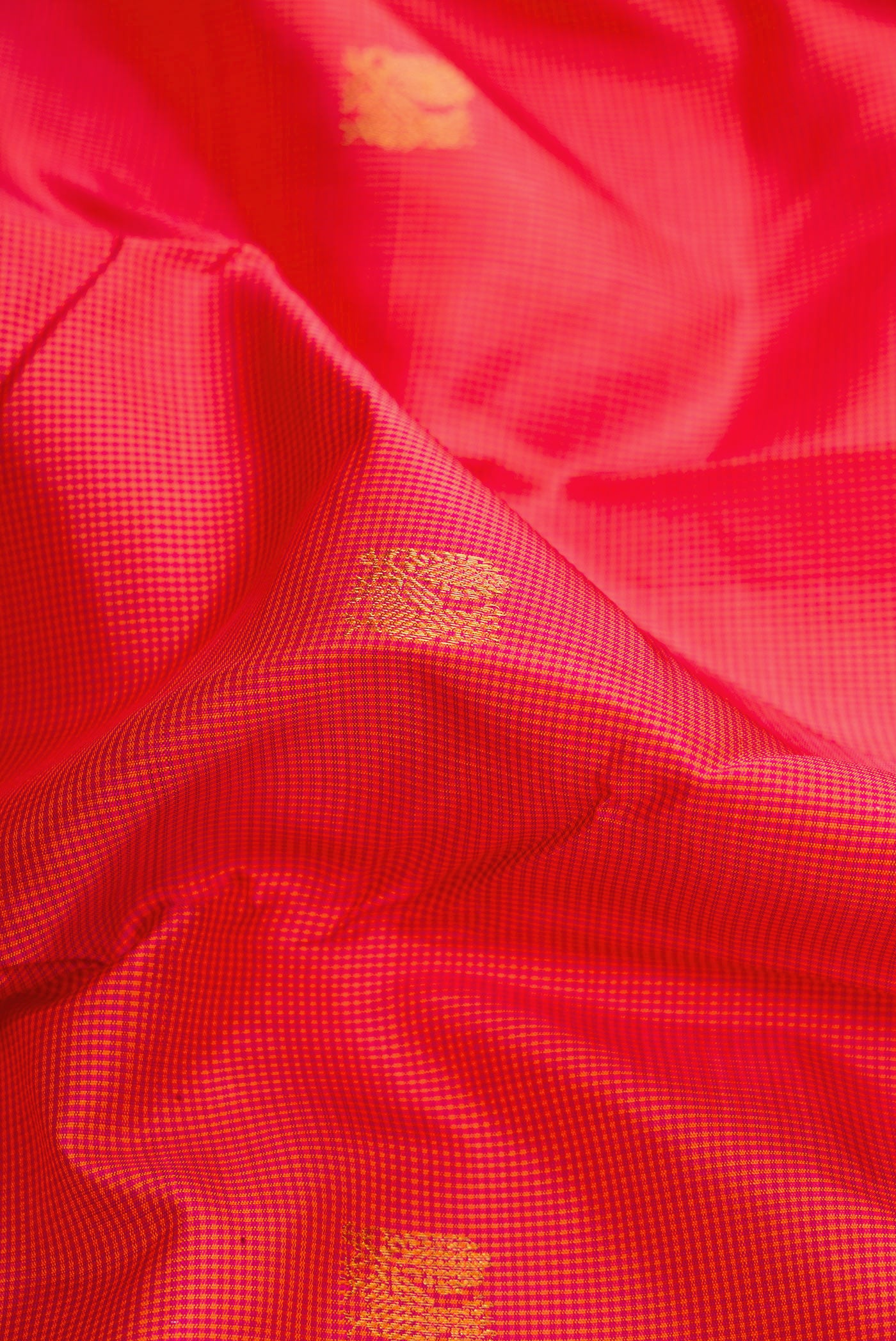 Close up of Coral Dual Tone Kanchipuram Silk Saree with Checked design on the body and Zari Border.  displaying folds