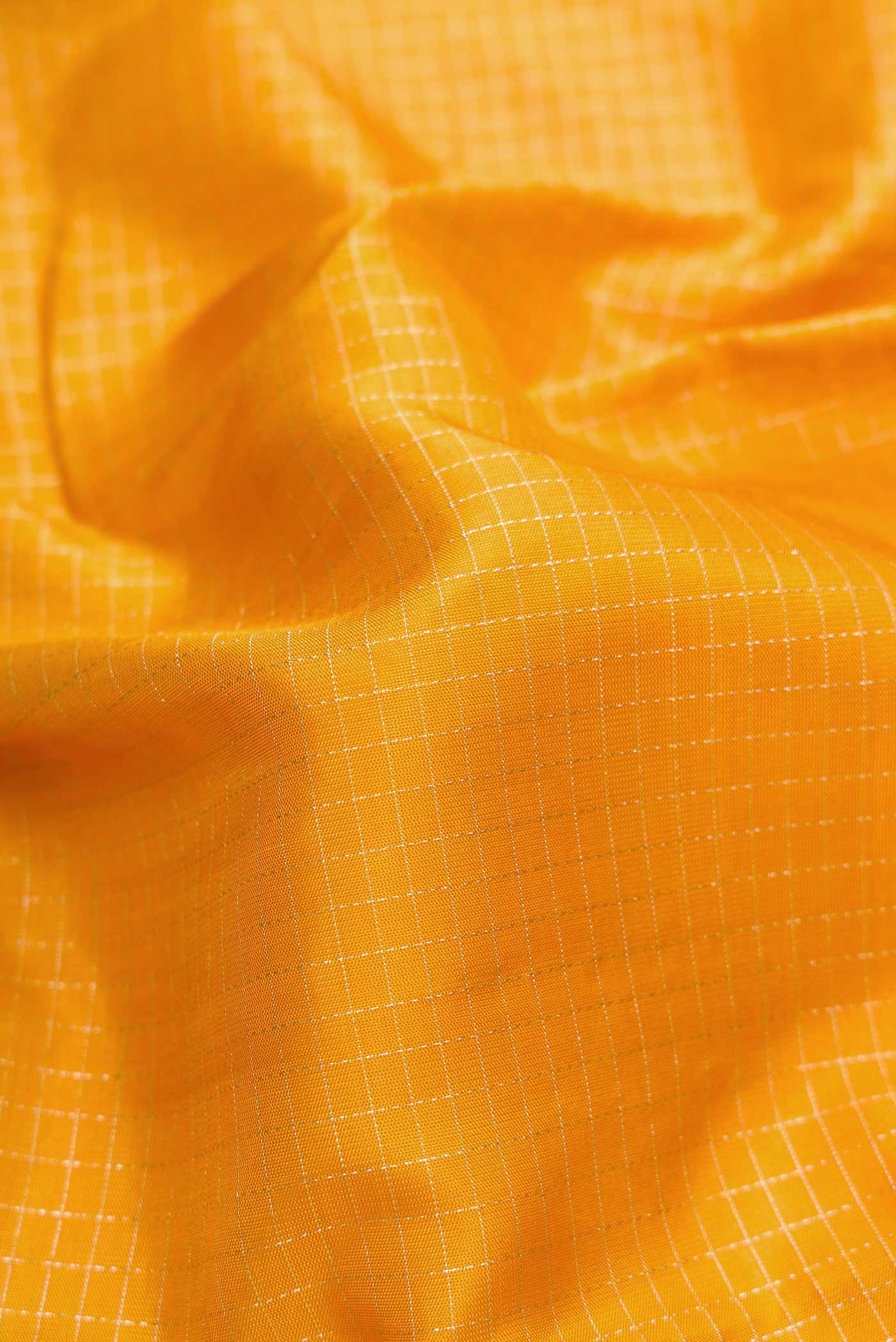 Close up of Mustard Dual Tone Kanchipuram Silk Saree with Checked design on the body and Zari Border.  displaying folds