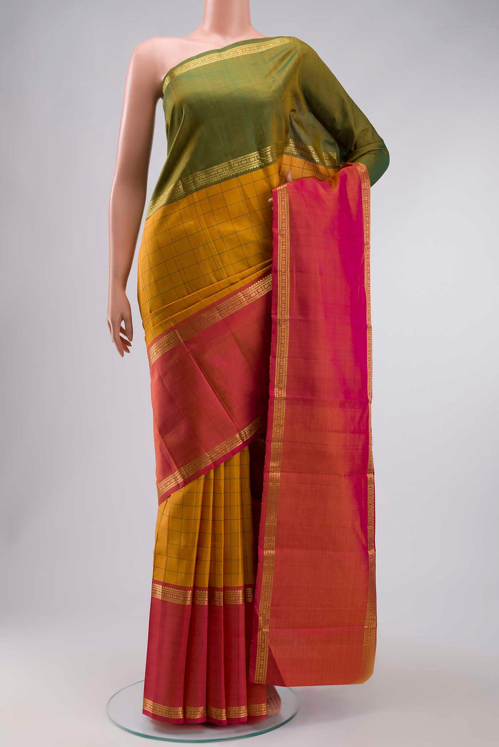 Mustard Kanchipuram Silk Saree with Checked design on the body and Ganga Jamuna Border displayed on a mannequin