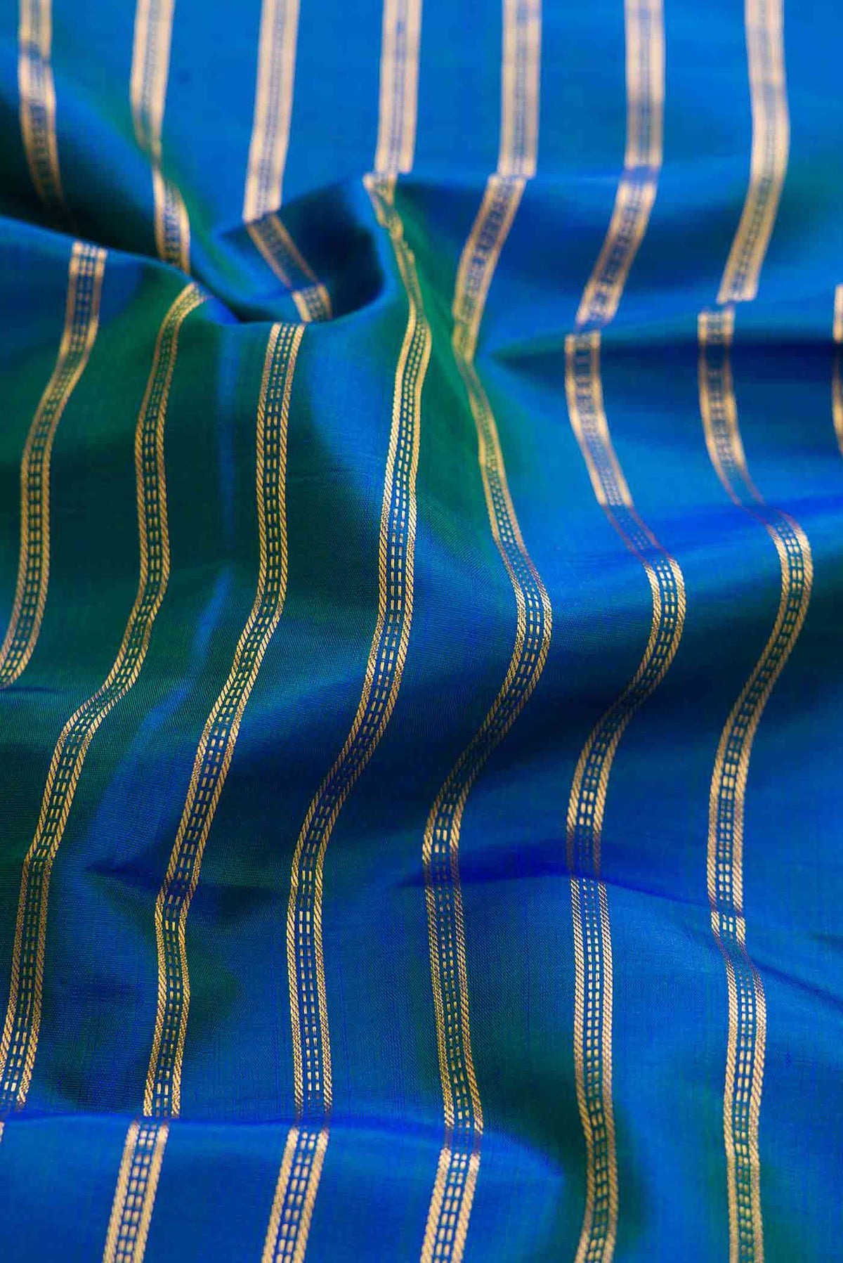 Close up of Peacock Blue Dual Tone Kanchipuram Silk Saree with Stripes on the body and Zari Border displaying folds