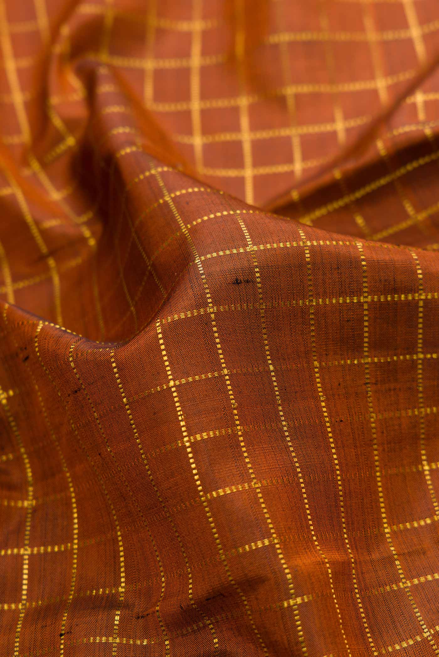 Close up of Brown Dual Tone Kanjivaram Silk Saree with Checked design on the body and Zari Border.  displaying folds