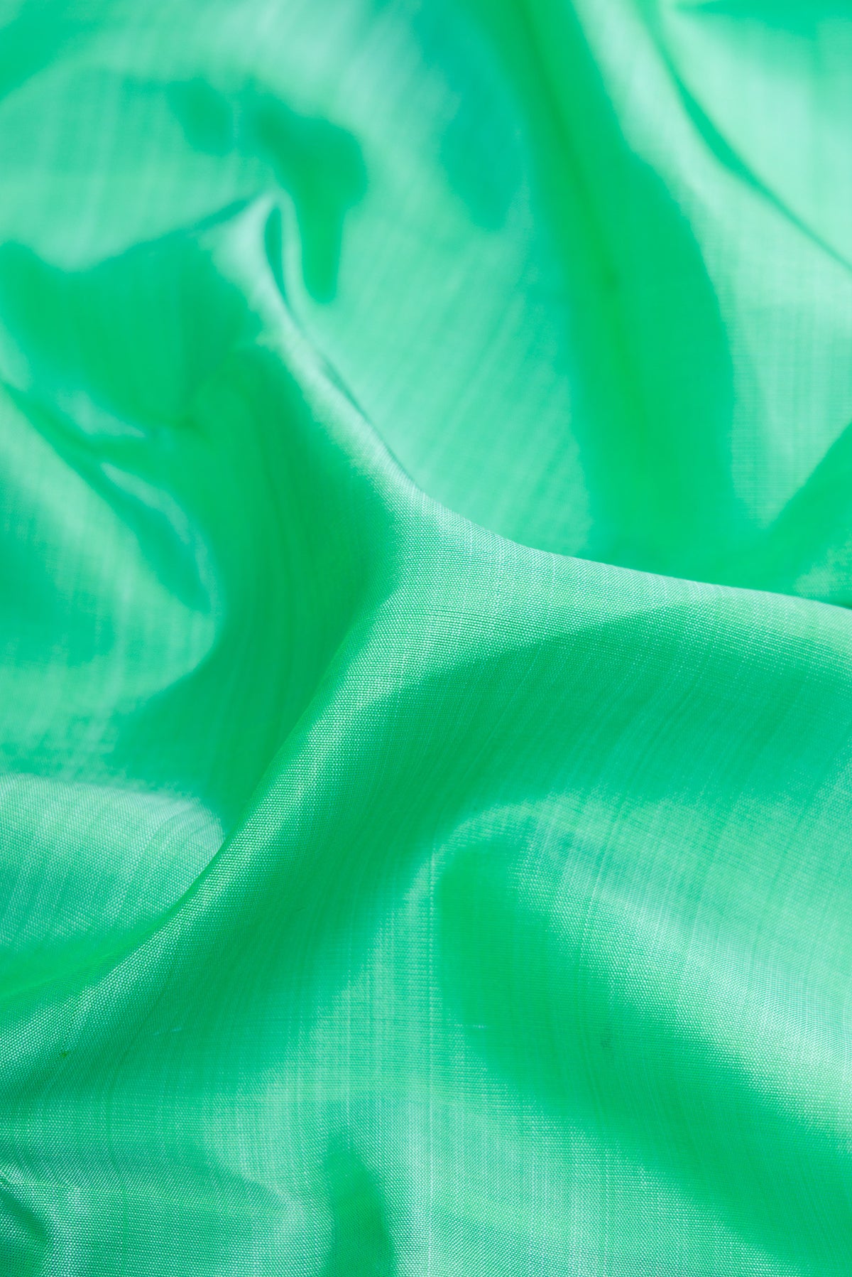 Close up of Pure Silk Pure Zari Sea Green Dual Tone Kanjivaram Saree with Plain Body and Zari Border.  displaying folds