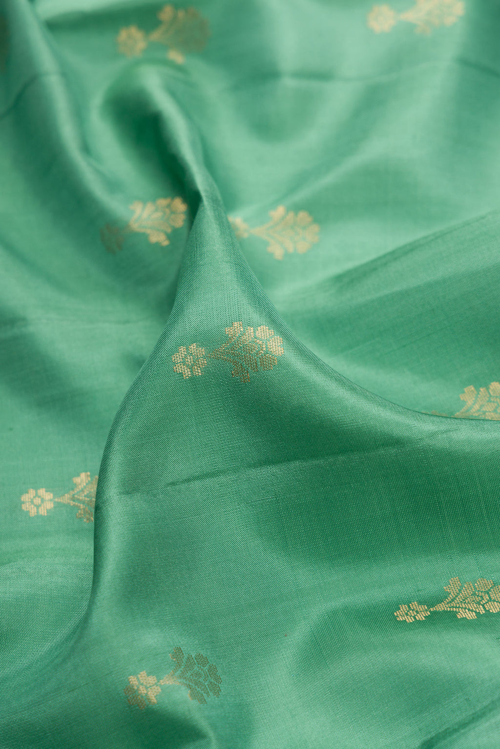 Close up of Green Dual Tone Soft Silk Saree with Zari Butta on the body and Zari Border.  displaying folds