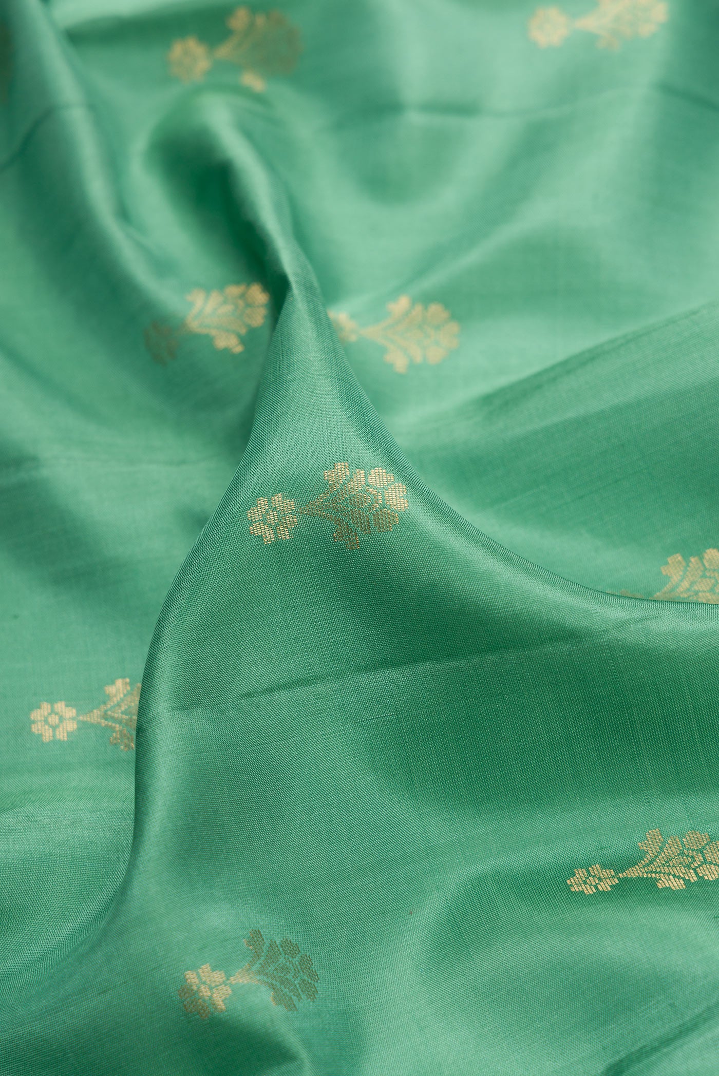 Close up of Green Dual Tone Soft Silk Saree with Zari Butta on the body and Zari Border.  displaying folds