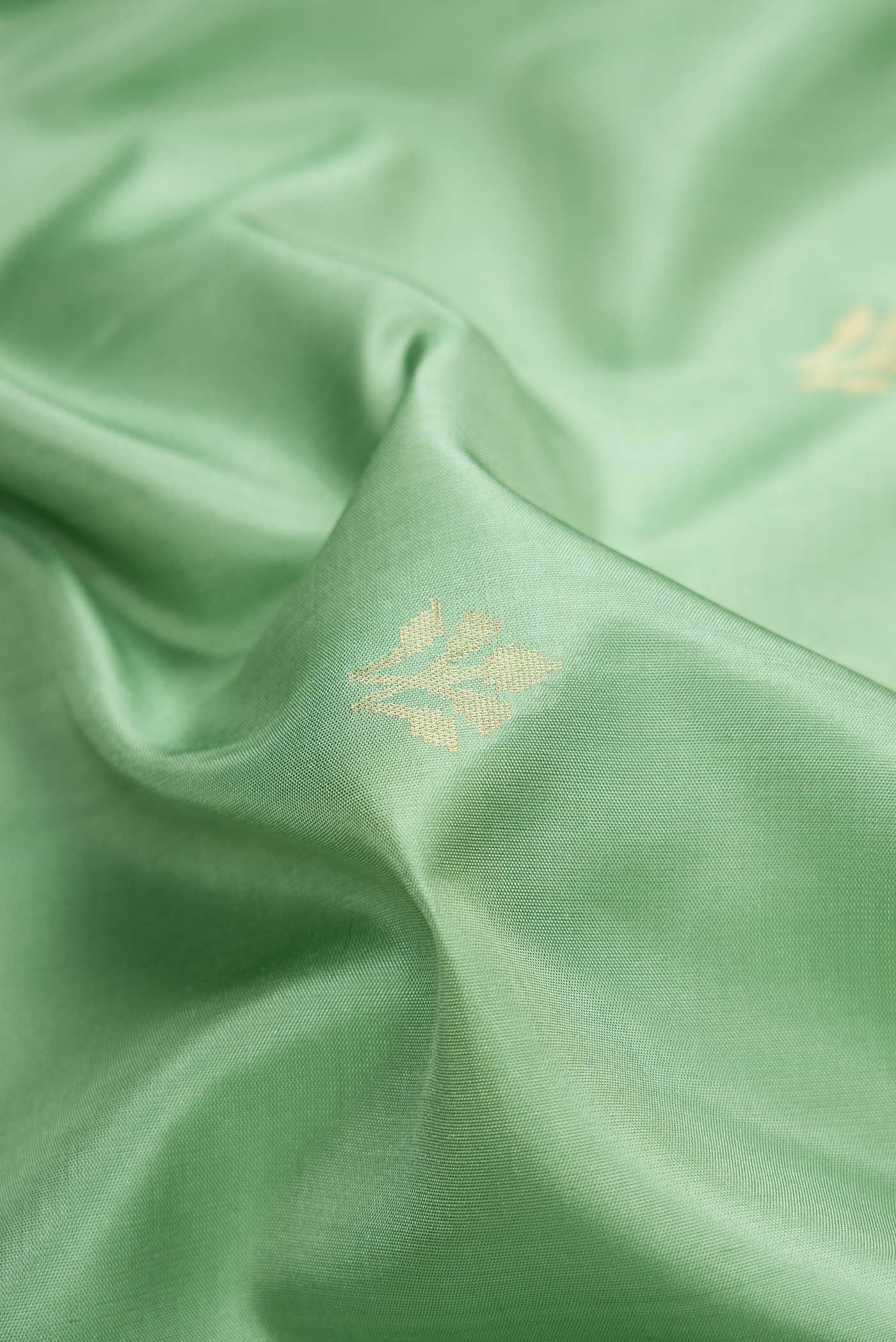 Close up of Pista Green Dual Tone Soft Silk Saree with Zari Butta on the body and Zari Border.  displaying folds