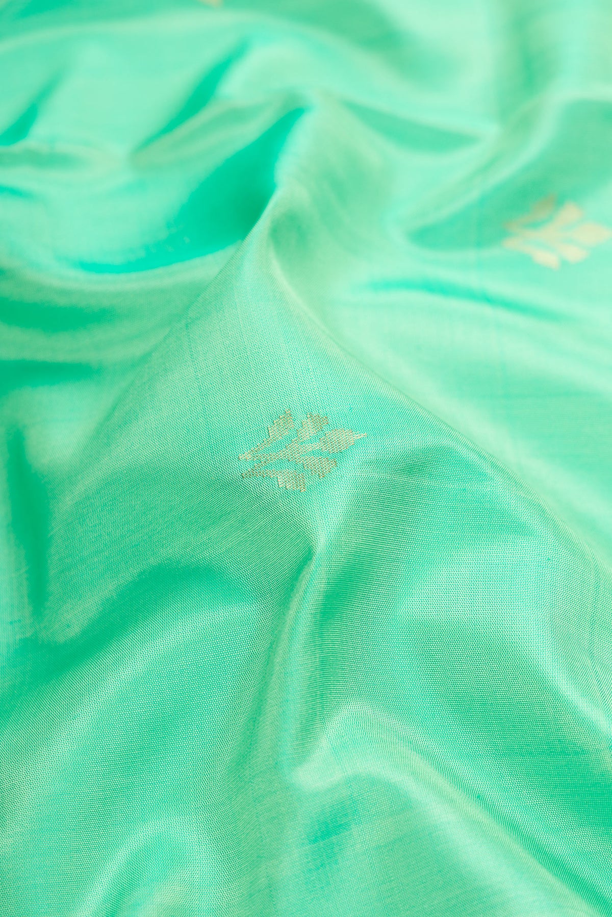 Close up of Parrot Green Dual Tone Soft Silk Saree with Zari Butta on the body and Zari Border.  displaying folds