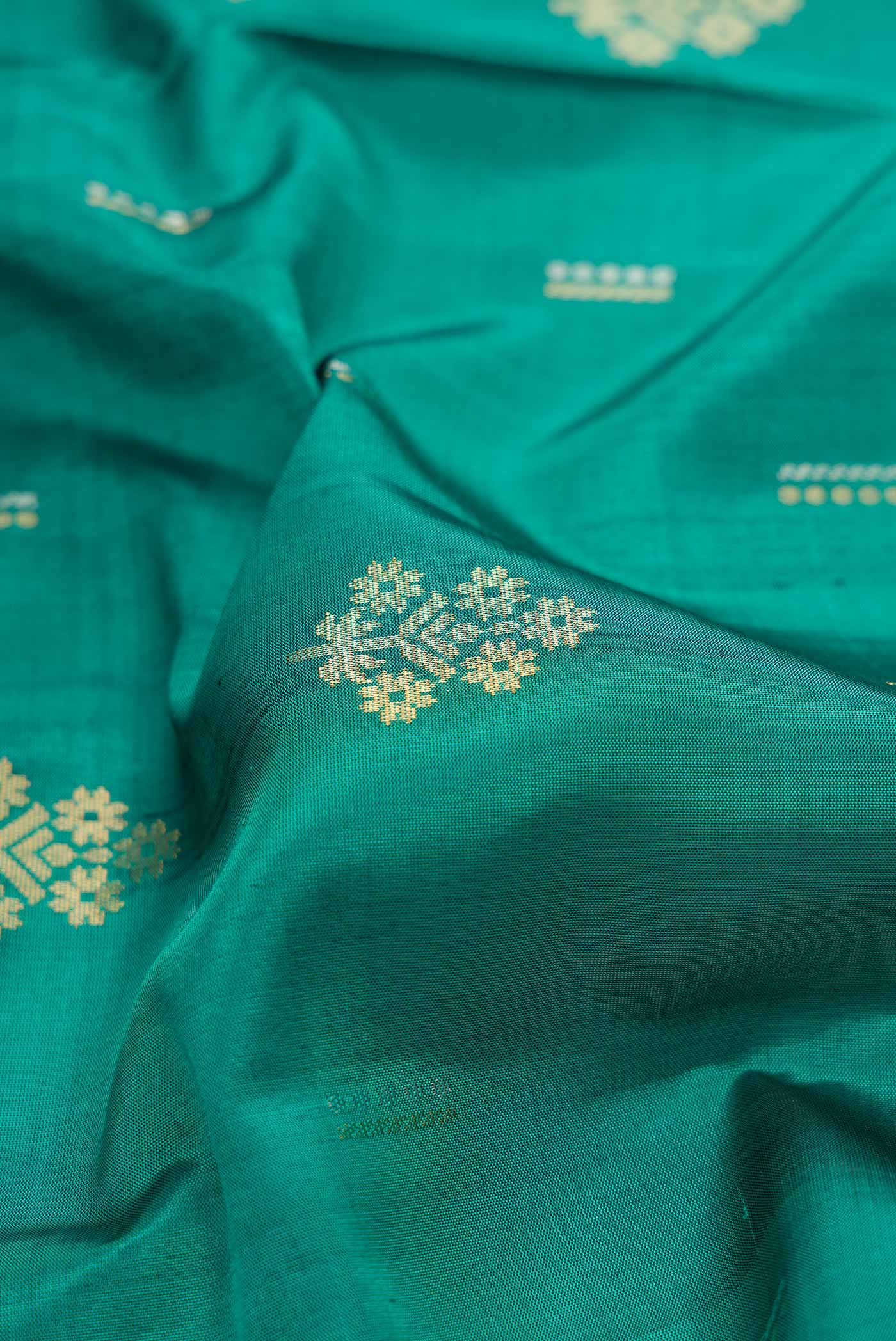 Close up of Green Dual Tone Soft Silk Saree with Zari Butta on the body and Zari Border.  displaying folds