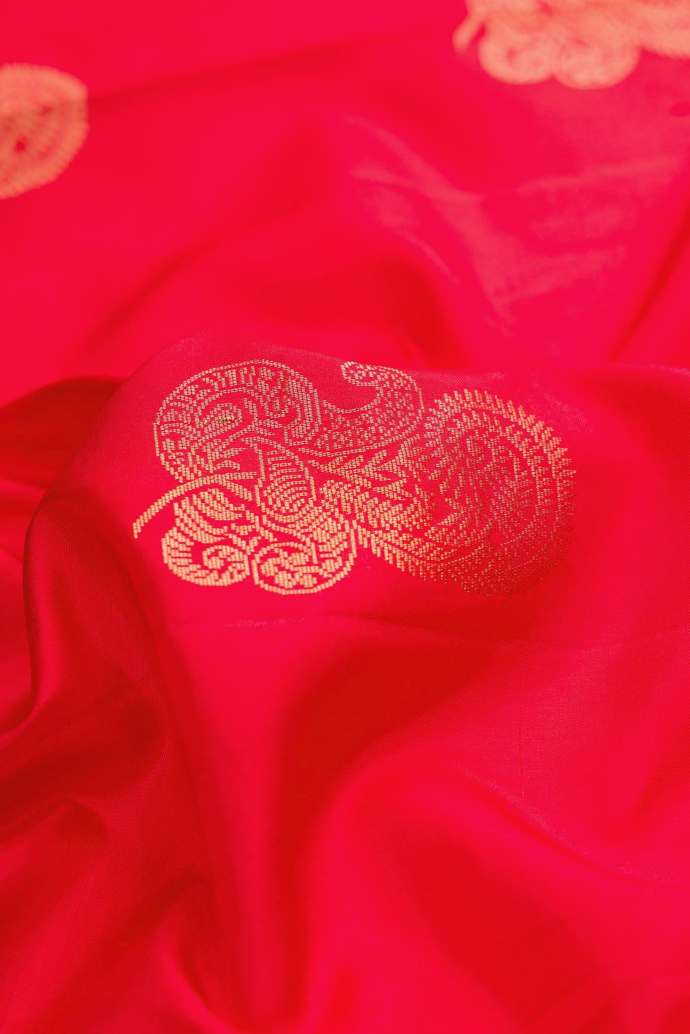 Close up of Red Dual Tone Soft Silk Saree with Zari Butta on the body and Without Border.  displaying folds