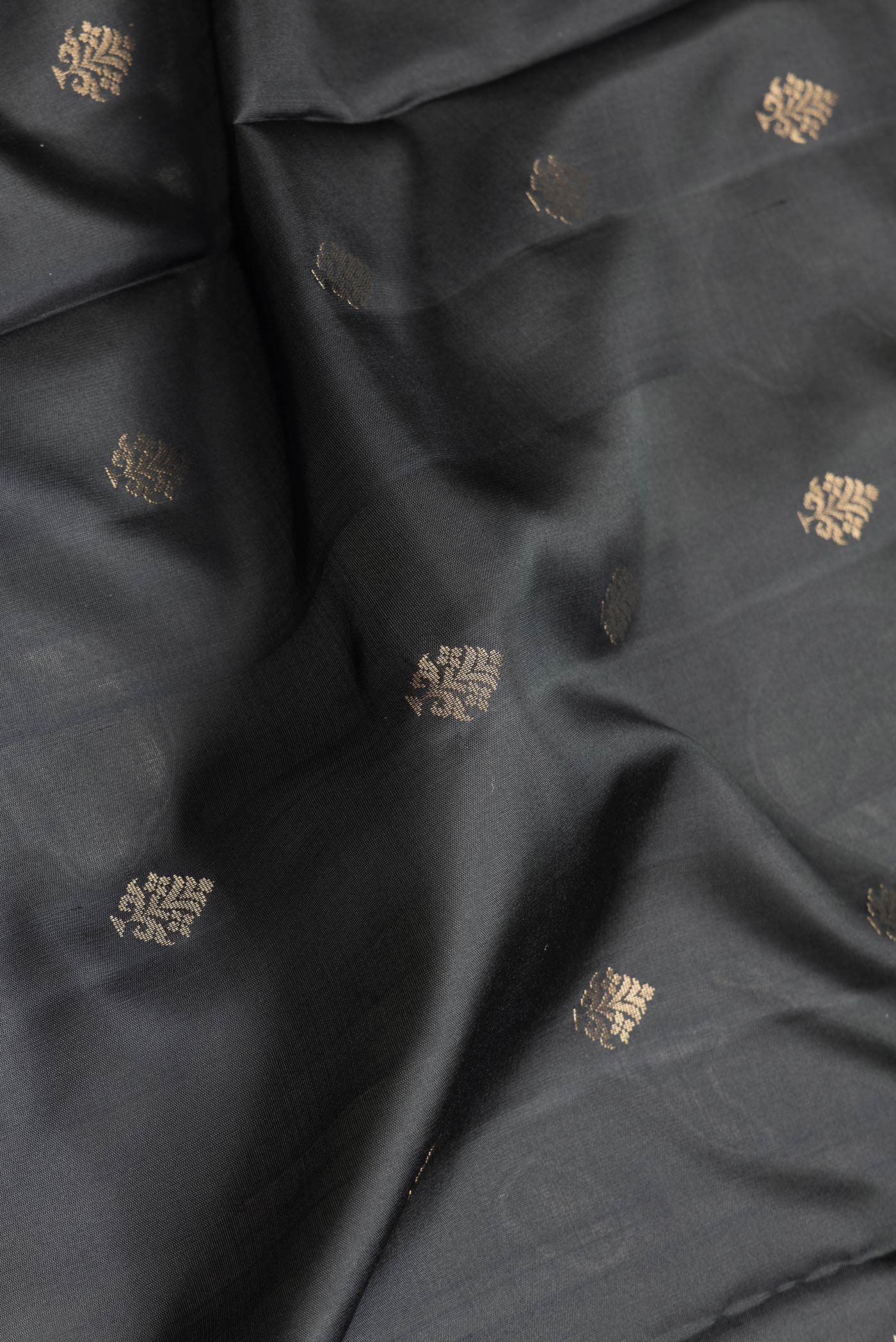 Close up of Black Dual Tone Soft Silk Saree with Zari Butta on the body and Zari Border.  displaying folds