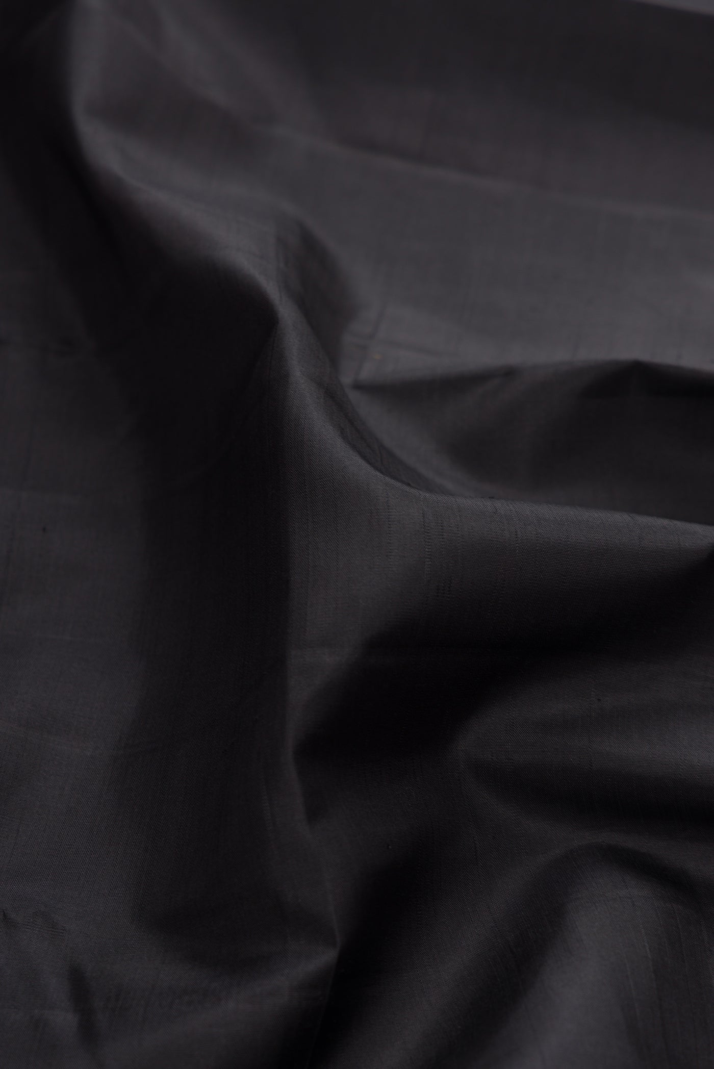 Close up of Pure Silk Pure Zari Black Dual Tone Kanchipuram Saree with Plain Body and Checks Border.  displaying folds
