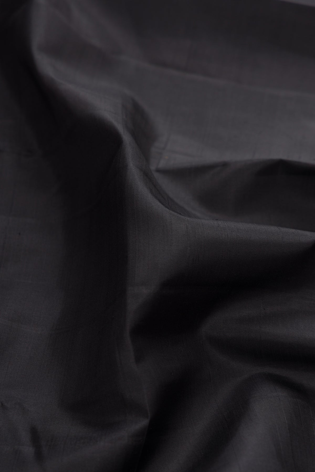 Close up of Pure Silk Pure Zari Black Dual Tone Kanchipuram Saree with Plain Body and Checks Border.  displaying folds