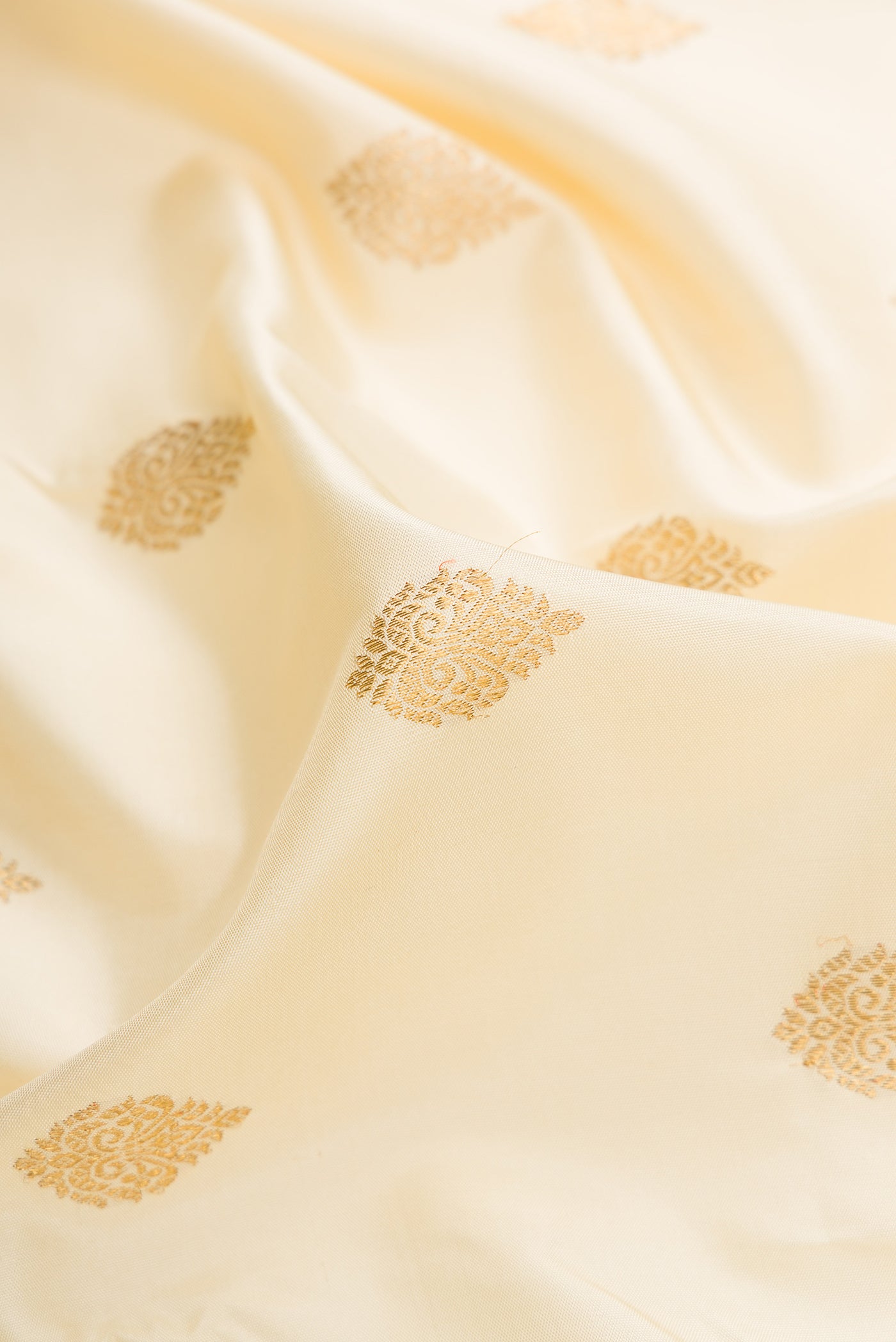 Close up of Pure Silk Pure Zari Off White Dual Tone Kanjivaram Saree with Zari Butta on the body and Zari Border.  displaying folds
