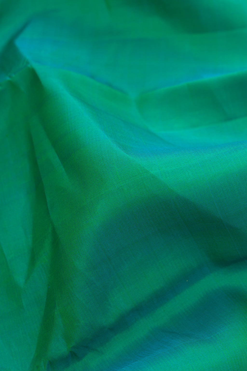 Close up of Pure Silk Pure Zari Green Dual Tone Kanchipuram Saree with Plain Body and Zari Border.  displaying folds
