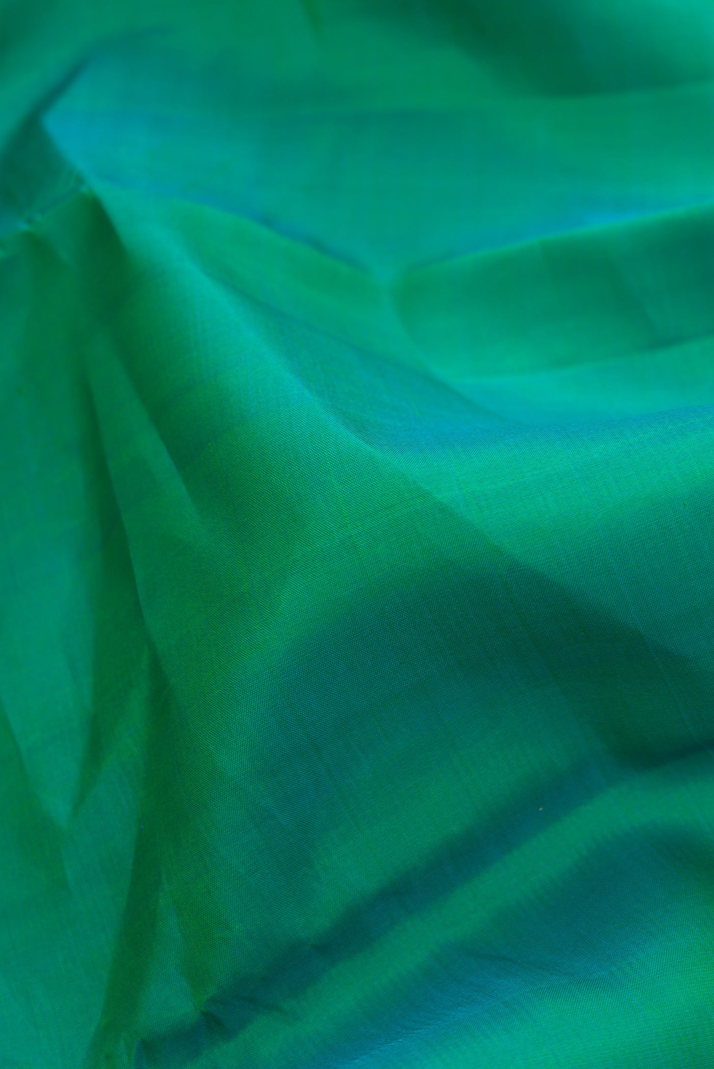 Close up of Pure Silk Pure Zari Green Dual Tone Kanchipuram Saree with Plain Body and Zari Border.  displaying folds