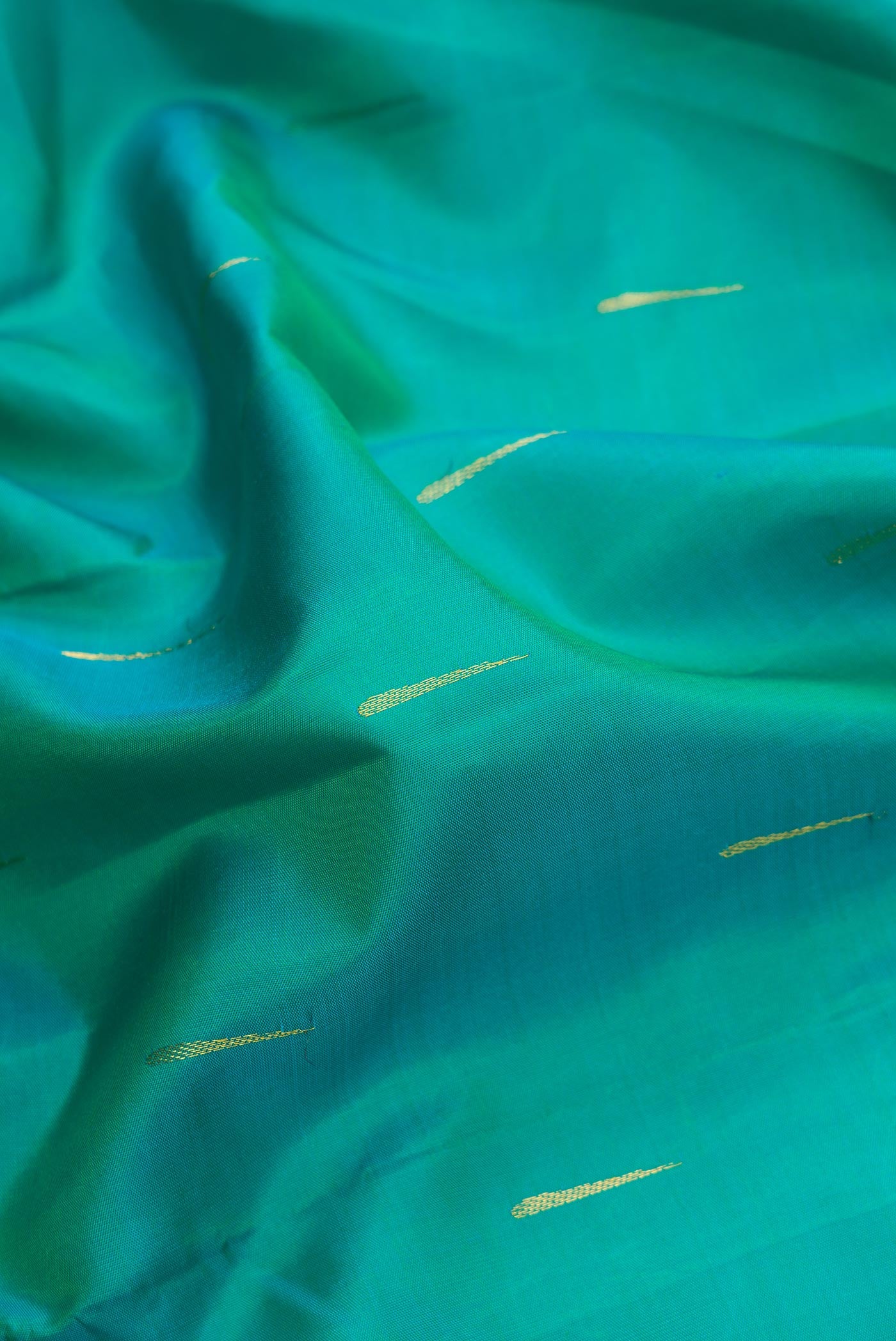 Close up of Green Dual Tone Kanchipuram Silk Saree with Zari Butta on the body and Zari Border.  displaying folds