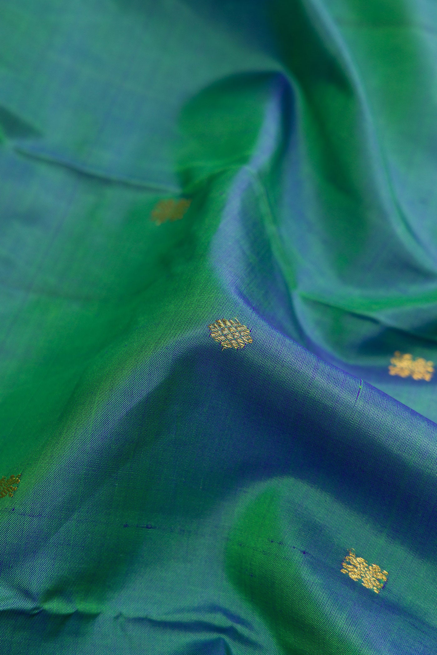 Close up of Peacock Blue Dual Tone Kanchipuram Silk Saree with Zari Butta on the body and Zari Border.  displaying folds