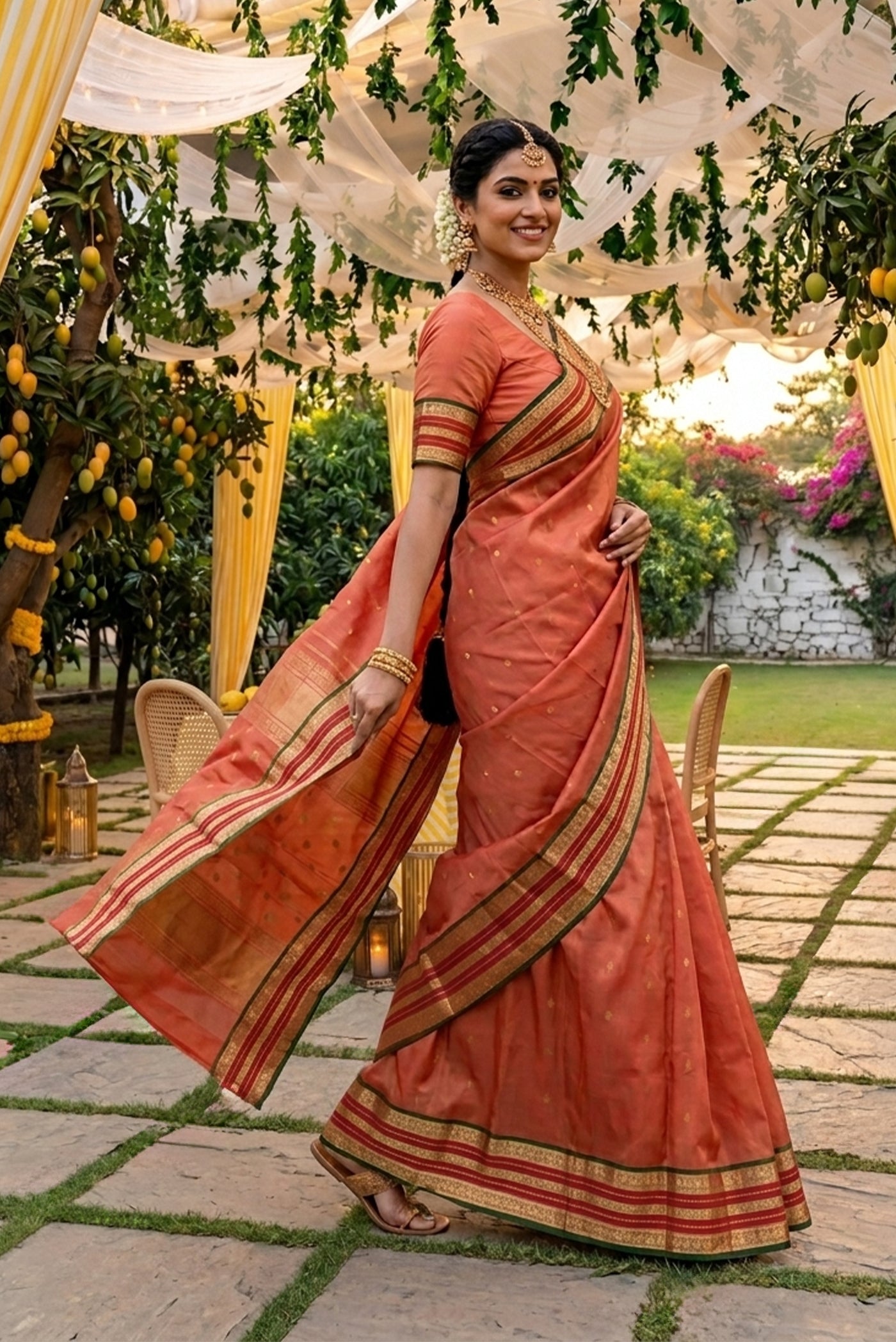 Model wearing a Coral Kanchipuram Silk Saree with Zari Butta on the body and Zari Border.