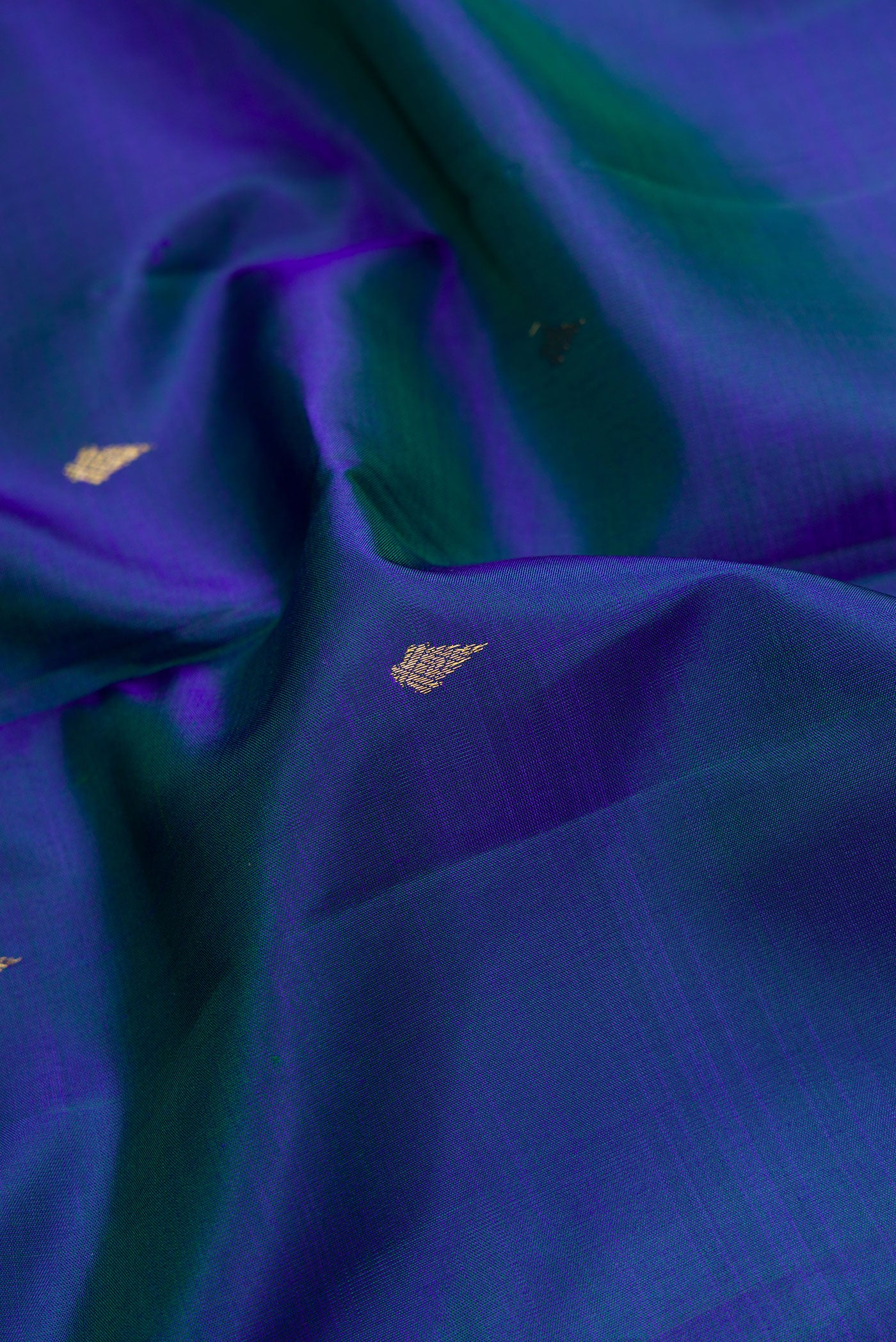 Close up of Peacock Blue Dual Tone Kanchipuram Silk Saree with Zari Butta on the body and Zari Border.  displaying folds