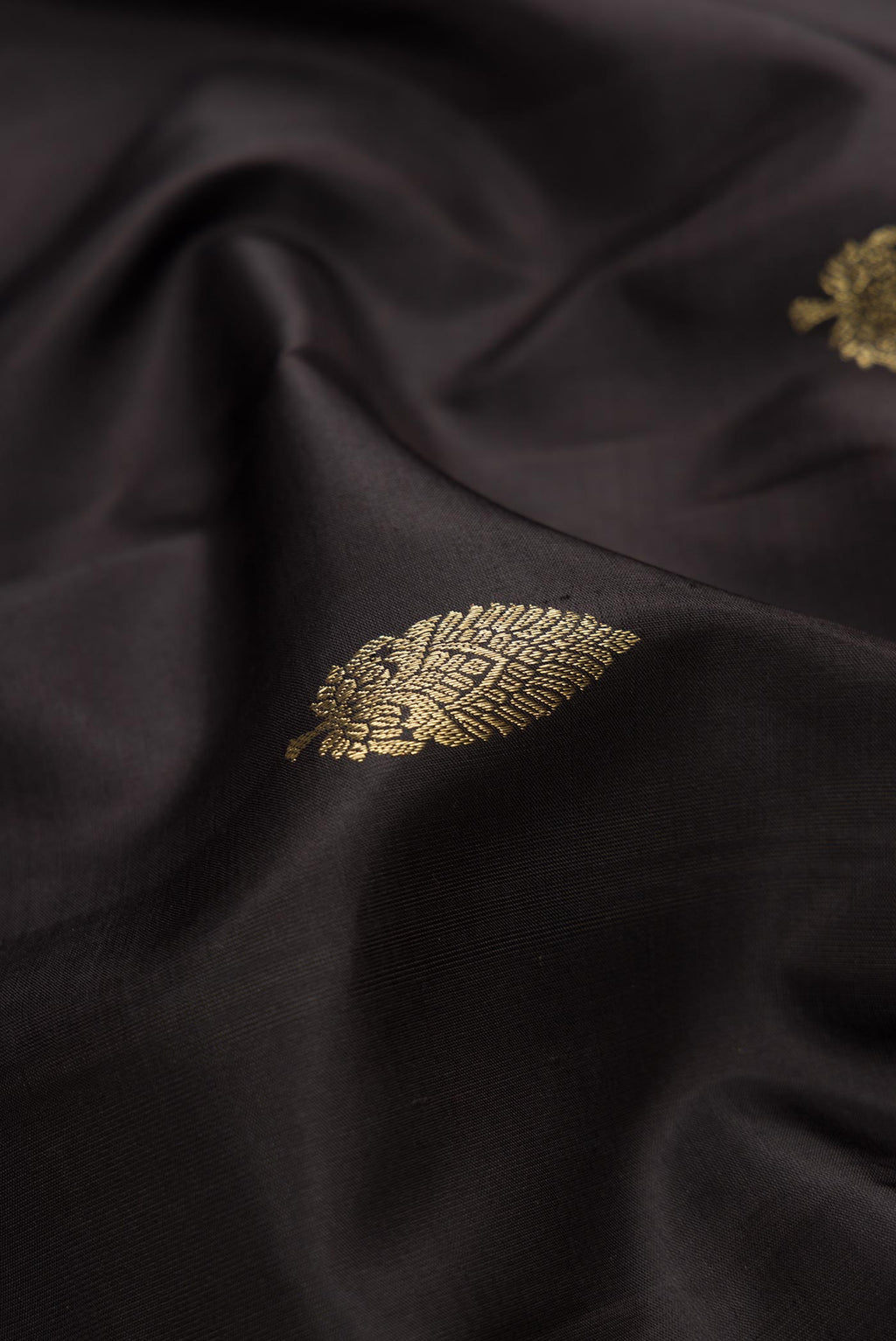 Close up of Black Dual Tone Kanchipuram Silk Saree with Zari Butta on the body and Zari Border.  displaying folds