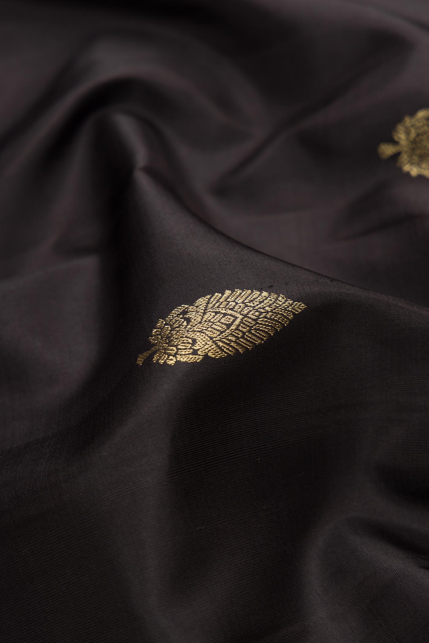 Close up of Black Dual Tone Kanchipuram Silk Saree with Zari Butta on the body and Zari Border.  displaying folds