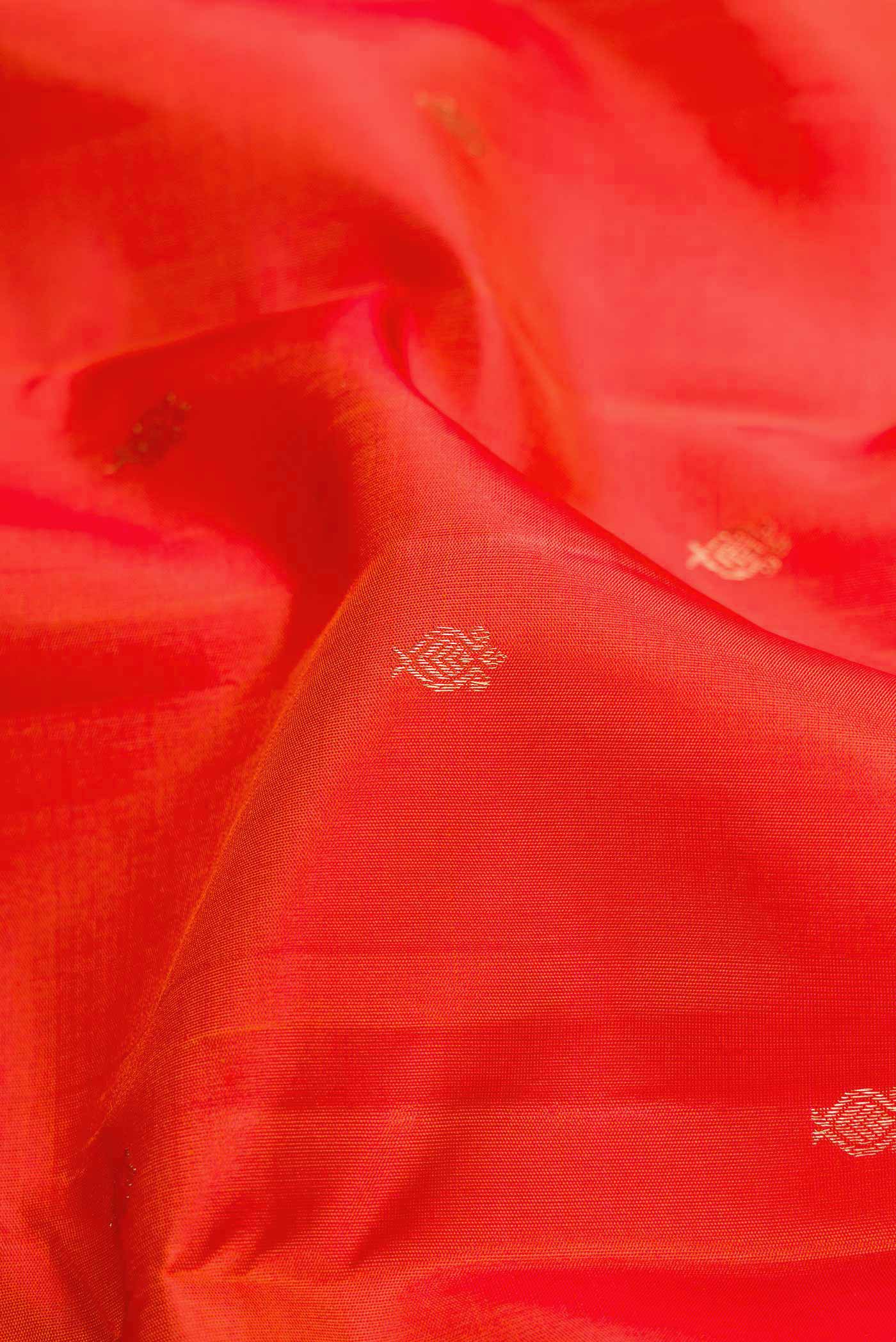 Close up of Orange Dual Tone Kanchipuram Silk Saree with Zari Butta on the body and Thread Border.  displaying folds