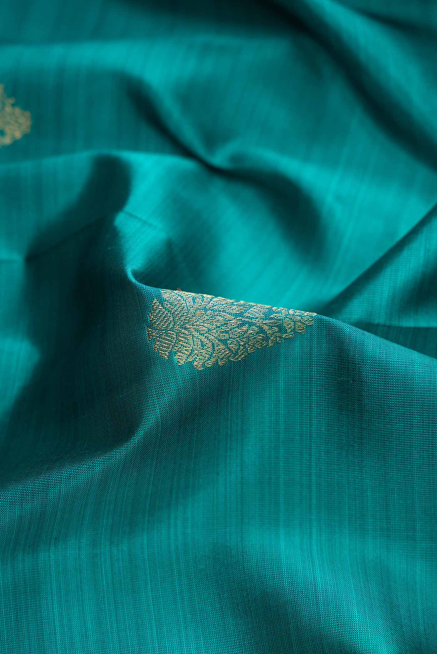 Close up of Green Dual Tone Kanchipuram Silk Saree with Zari Butta on the body and Zari Border.  displaying folds