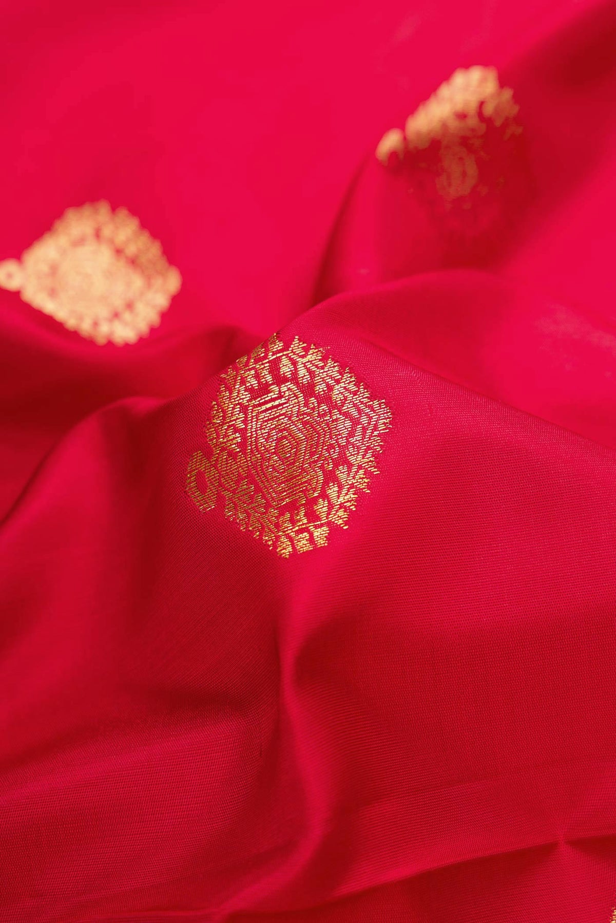 Close up of Red Dual Tone Kanjivaram Silk Saree with Zari Butta on the body and Zari Border.  displaying folds