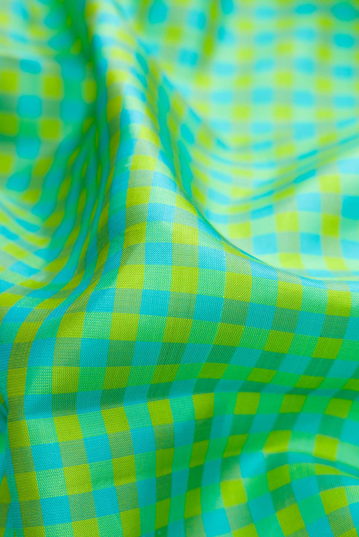 Close up of Green, Sea Green and Yellow Color Kanjivaram Silk Saree with Checked design on the body and Zari Border.  displaying folds