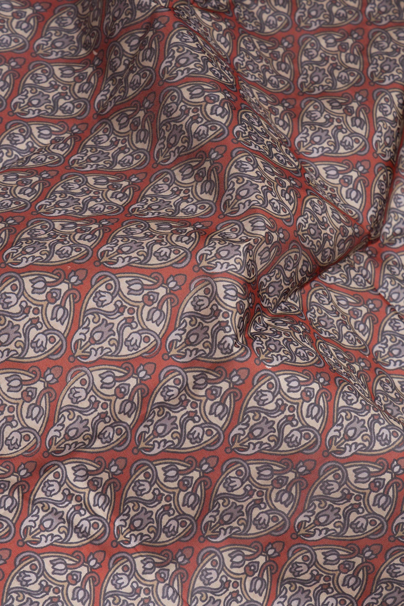 Close up of Brick Orange Printed Silk Saree with Printed design on the body and Printed Border.  displaying folds