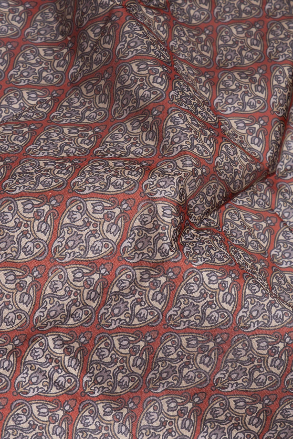Close up of Brick Orange Printed Silk Saree with Printed design on the body and Printed Border.  displaying folds