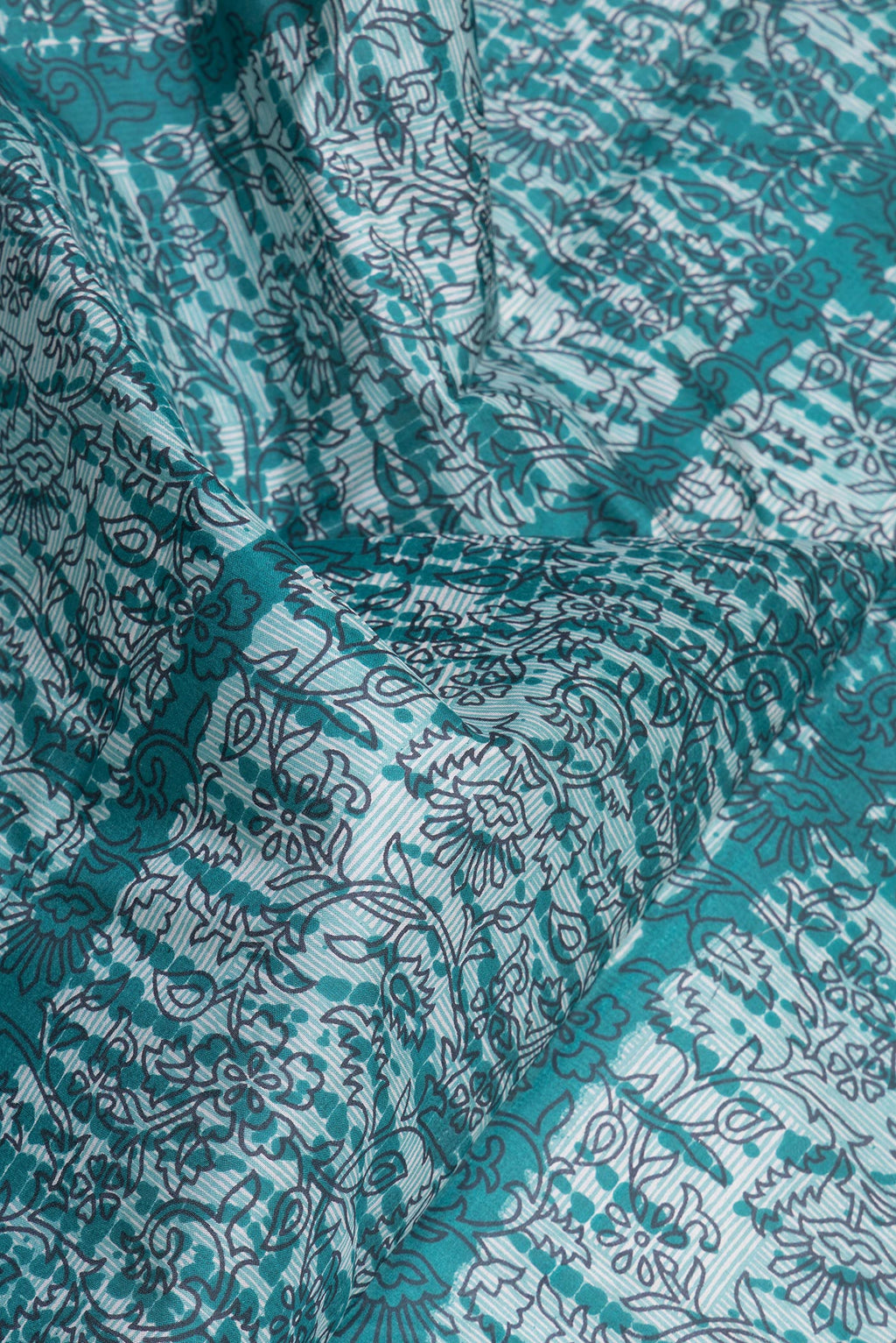 Close up of Peacock Blue Printed Silk Saree with Printed design on the body and Printed Border.  displaying folds
