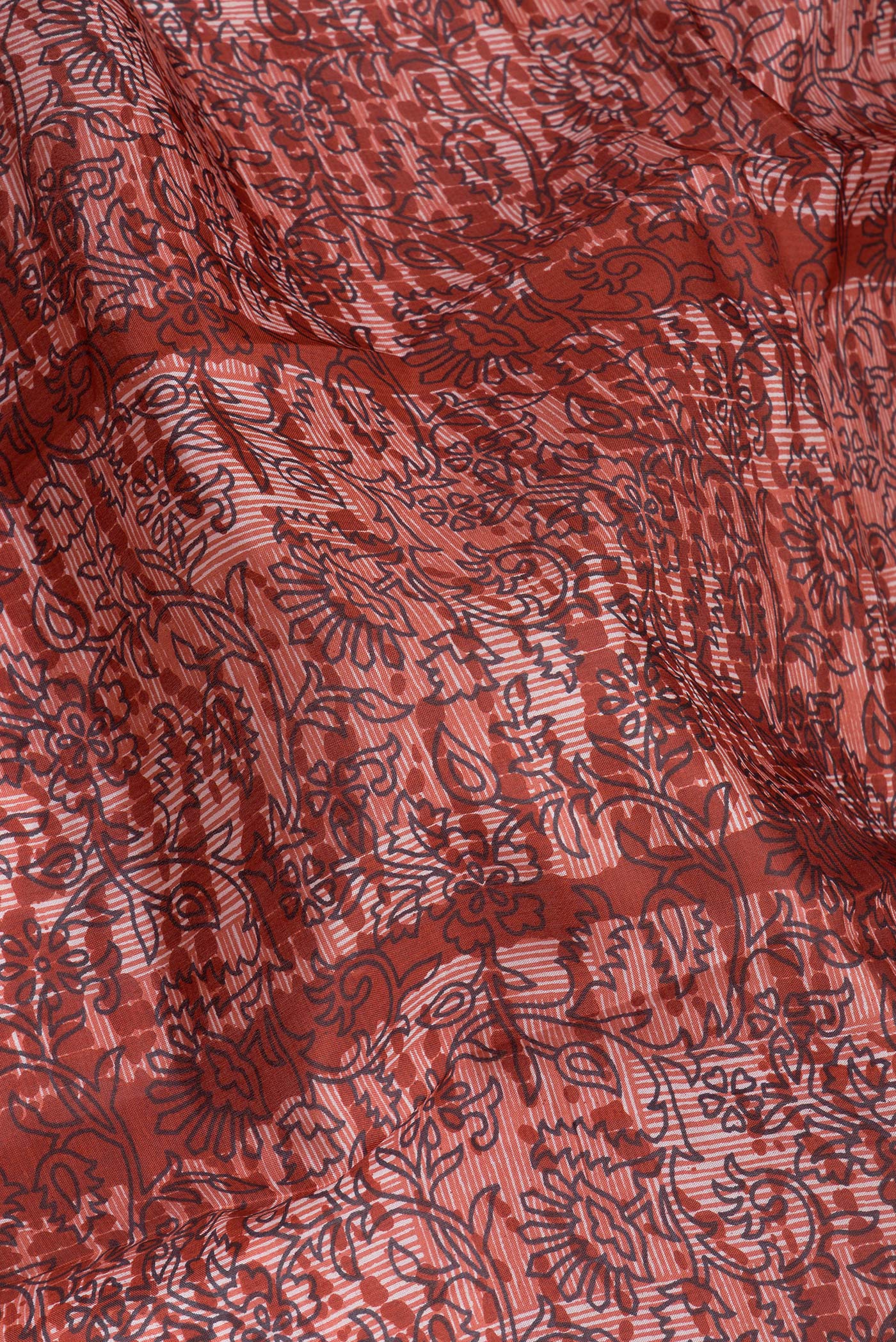Close up of Rust Printed Silk Saree with Printed design on the body and Printed Border.  displaying folds