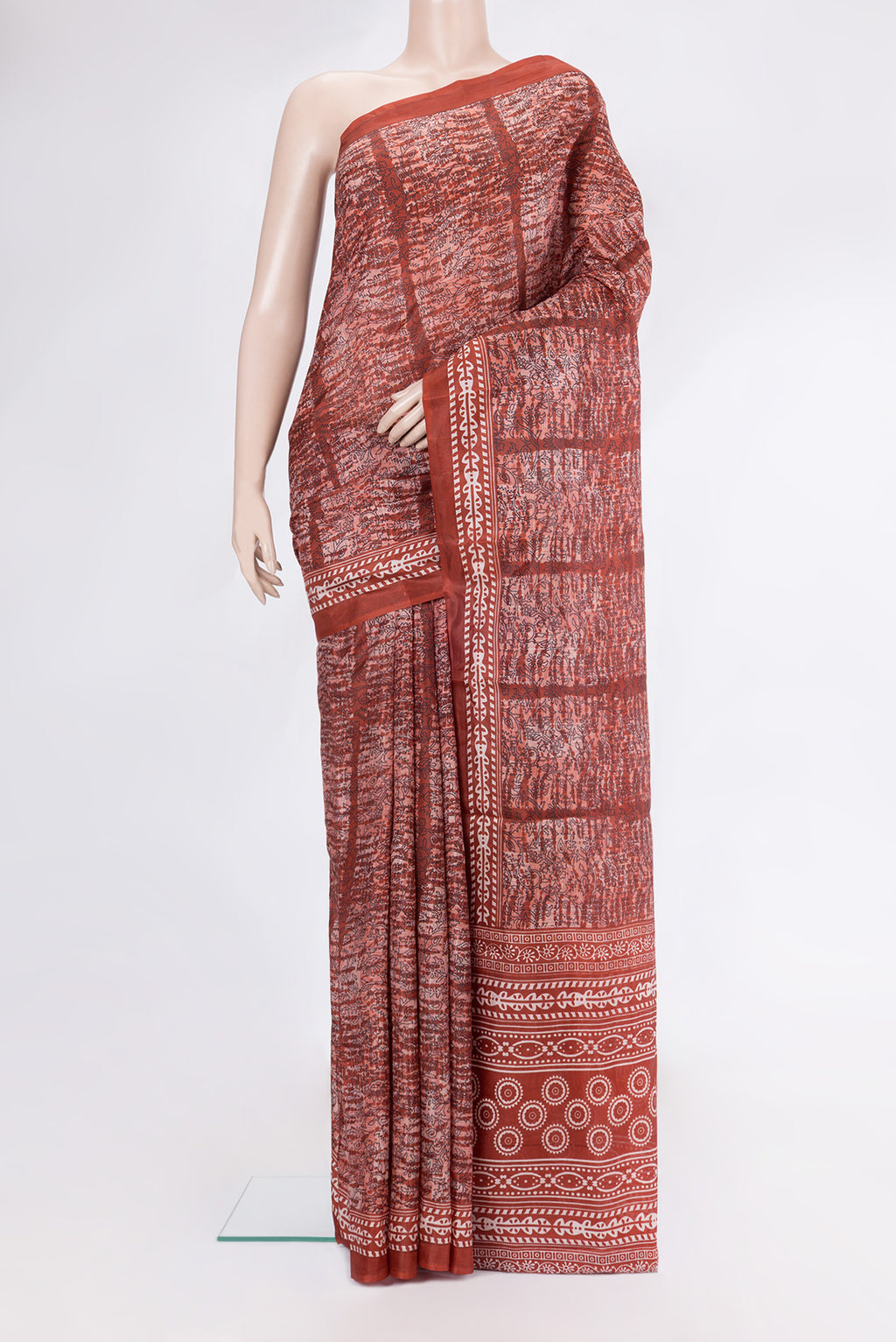 Rust Printed Silk Saree with Printed design on the body and Printed Border.  displayed on a mannequin