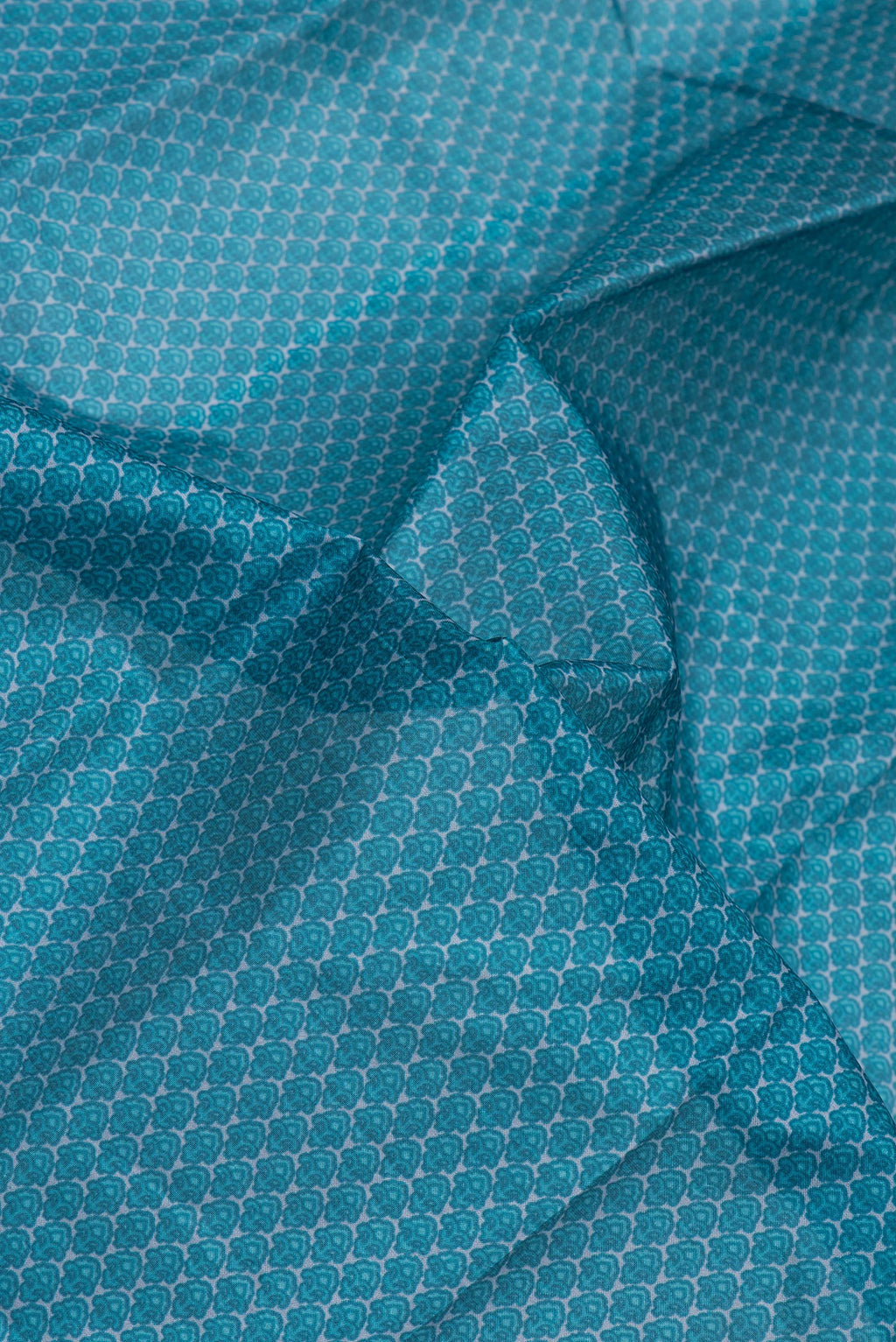 Close up of Peacock Blue Printed Silk Saree with Printed design on the body and Printed Border.  displaying folds