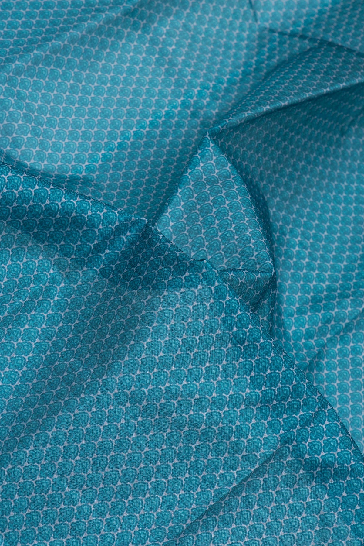 Close up of Peacock Blue Printed Silk Saree with Printed design on the body and Printed Border.  displaying folds