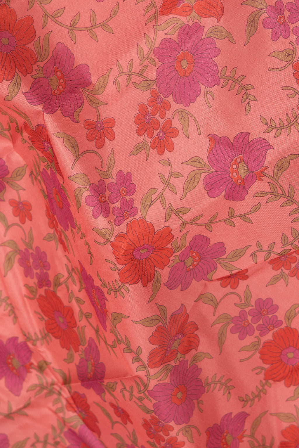 Close up of Coral Printed Silk Saree with Printed design on the body and Without Border.  displaying folds