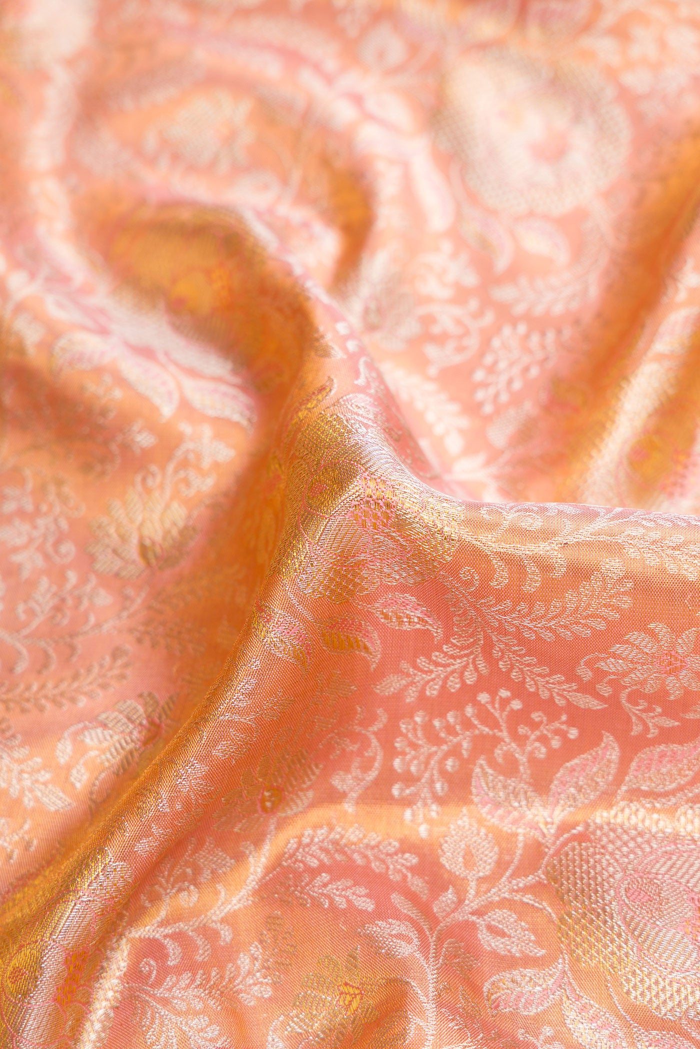 Close up of Rose Gold Dual Tone Kanjivaram Tissue Silk Saree with Zari Brocade on the body and Zari Border.  displaying folds