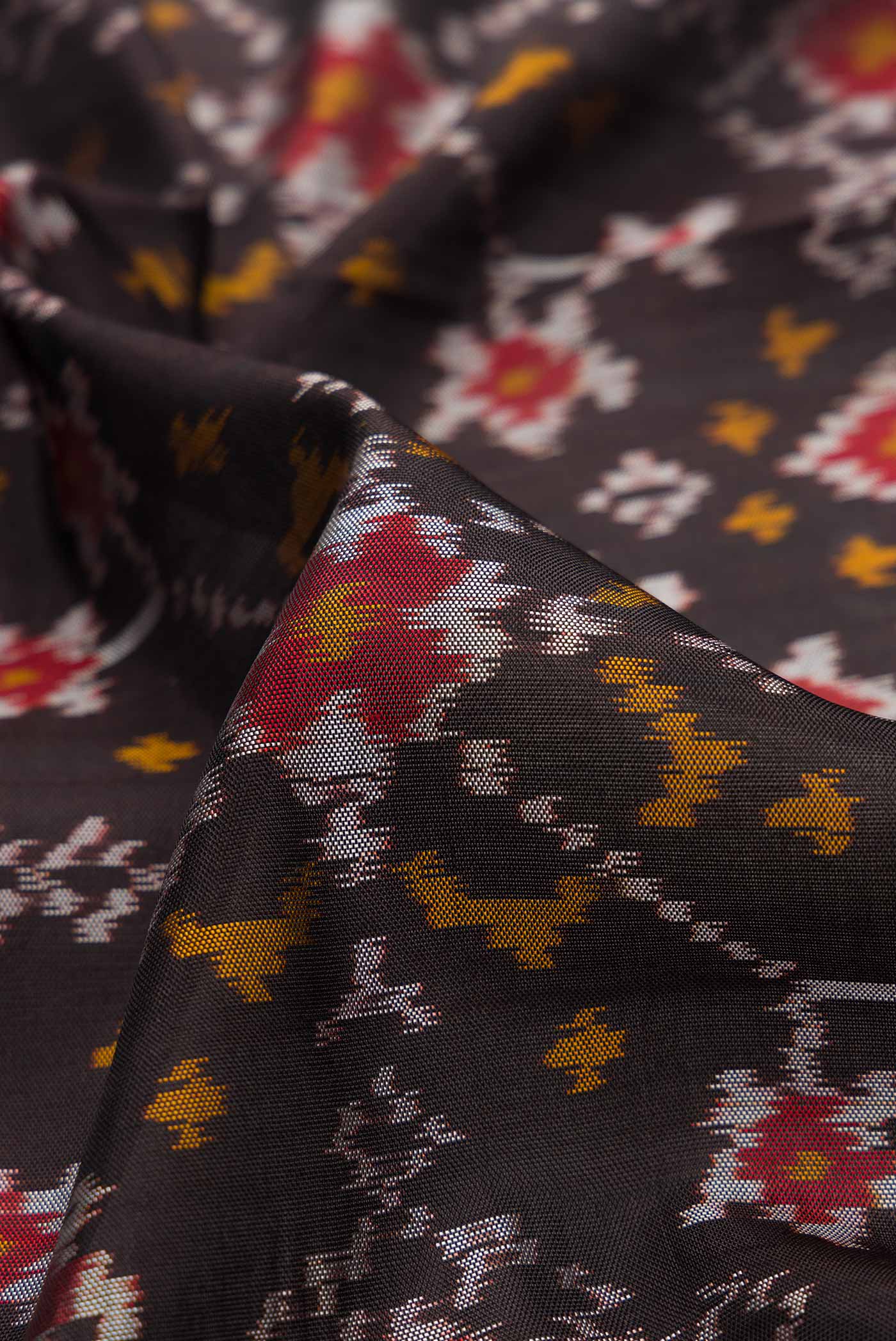 Close up of Black Dual Tone Rajkot Patola Silk Saree with Ikat Print on the body and Zari Border.  displaying folds