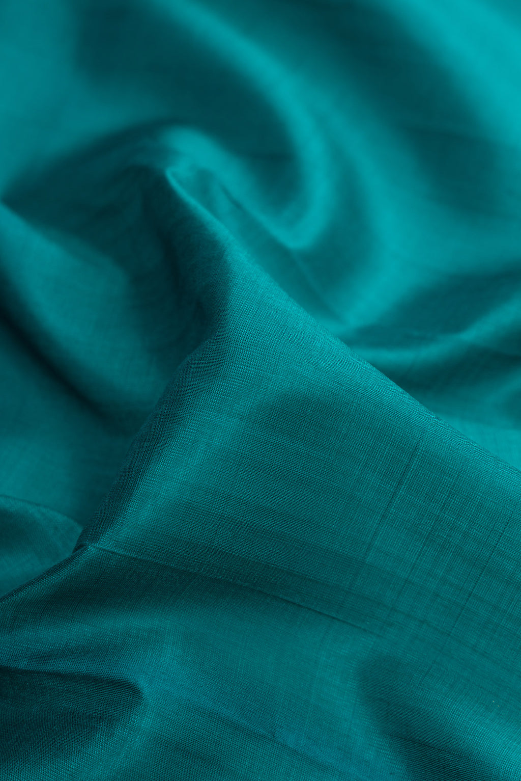 Close up of Peacock Blue Dual Tone Kanchipuram Silk Saree with Plain Body and Zari Border.  displaying folds
