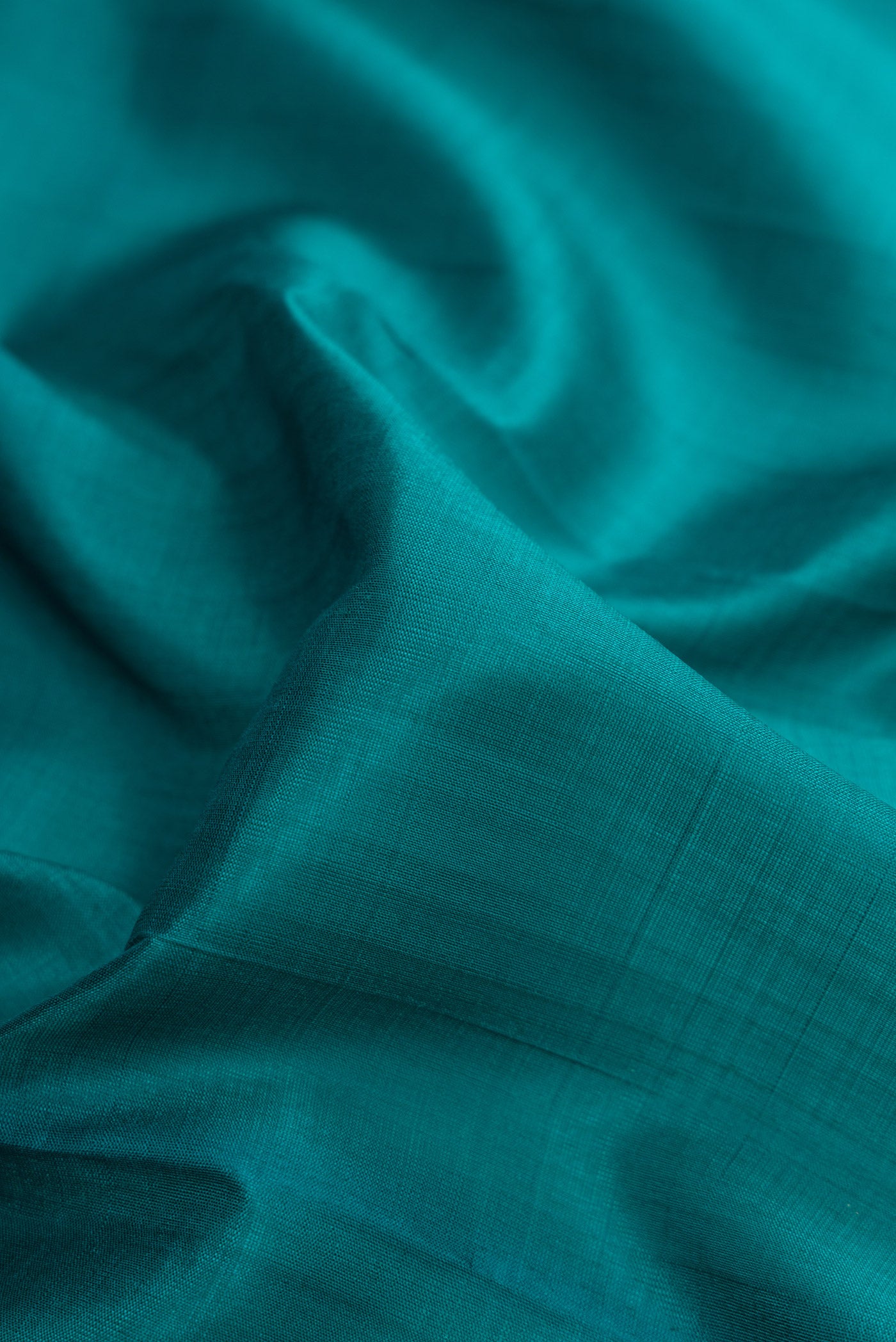 Close up of Peacock Blue Dual Tone Kanchipuram Silk Saree with Plain Body and Zari Border.  displaying folds