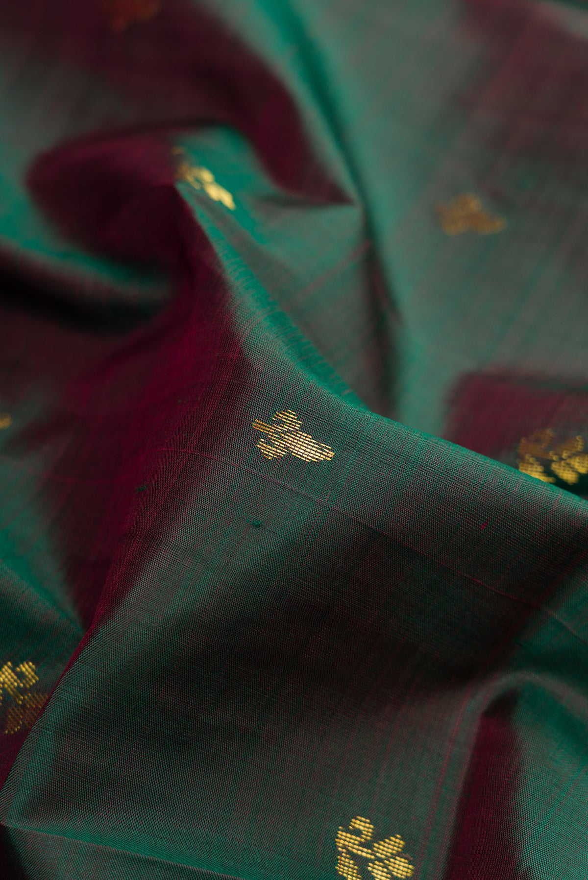 Close up of Bottle Green Dual Tone Kanchipuram Silk Saree with Zari Butta on the body and Zari Border.  displaying folds