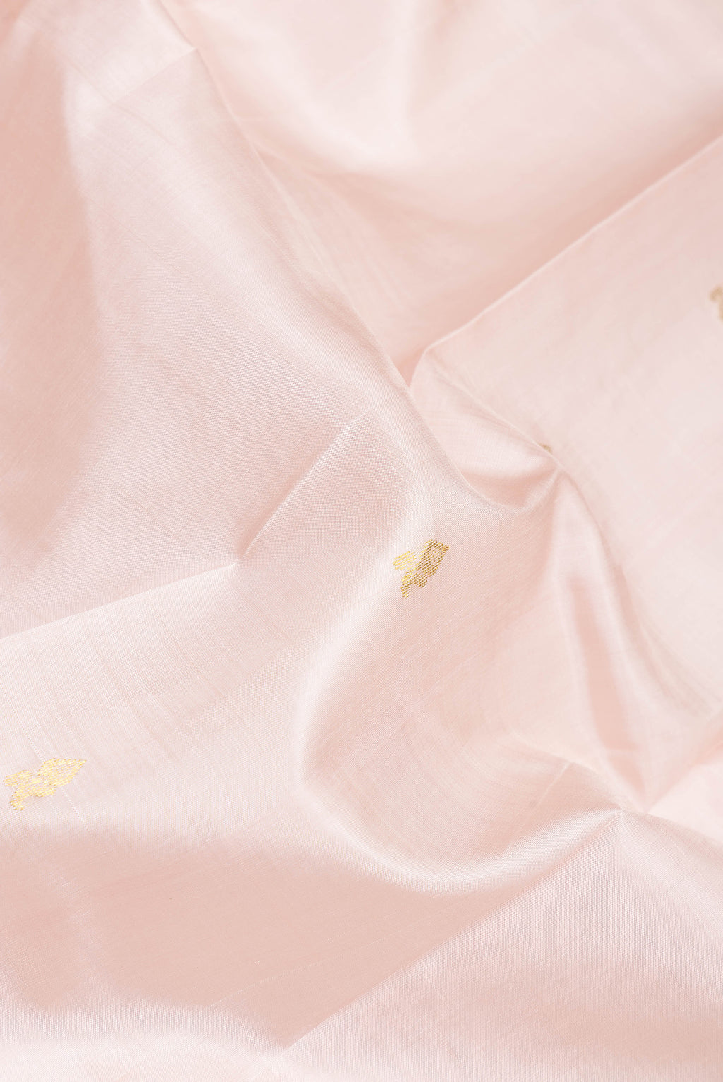 Close up of Rose Gold Kanjivaram Silk Saree with Zari Butta on the body and One Side Border.  displaying folds