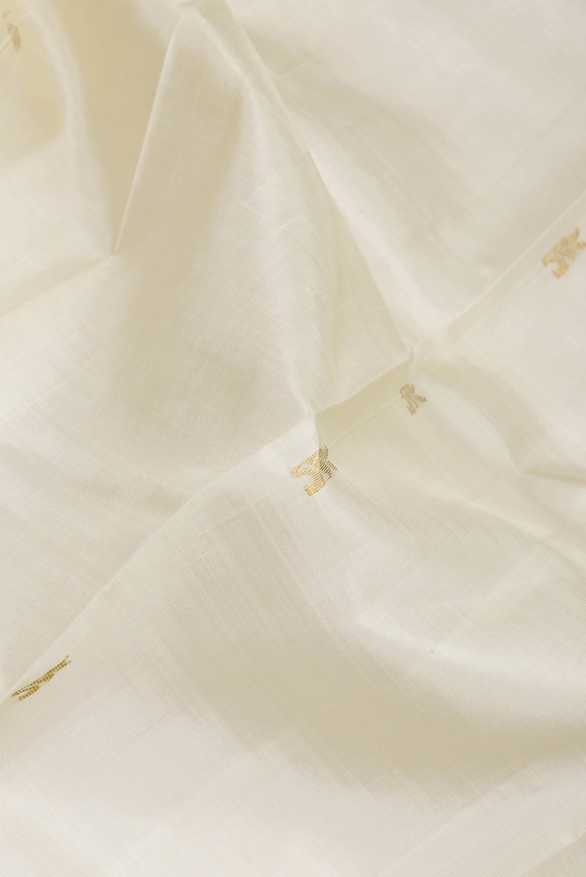Close up of Off White Kanjivaram Silk Saree with Zari Butta on the body and One Side Border.  displaying folds