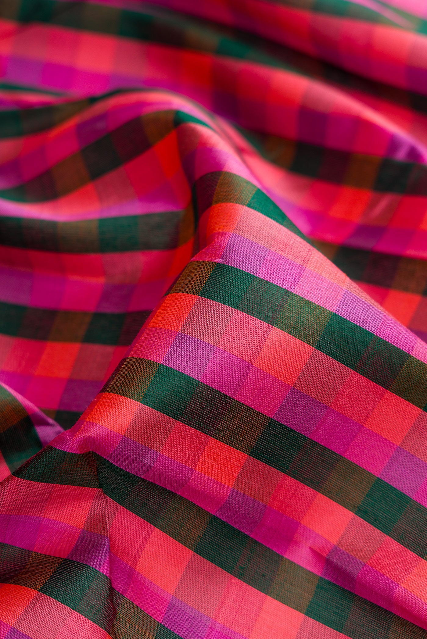 Close up of Bottle Green, Pink and Purple Color Kanjivaram Silk Saree with Checked design on the body and Zari Border.  displaying folds