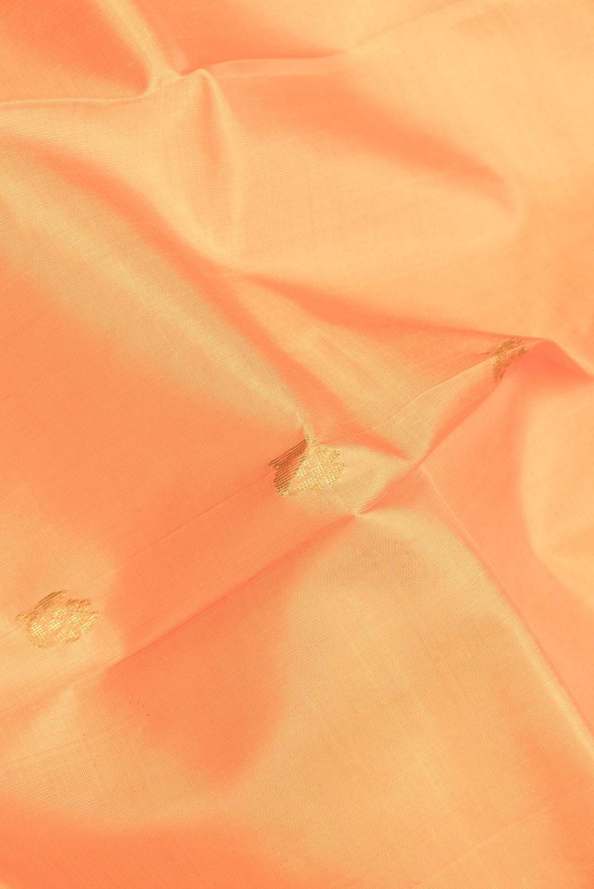 Close up of Orange Dual Tone Kanjivaram Silk Saree with Zari Butta on the body and One Side Border.  displaying folds