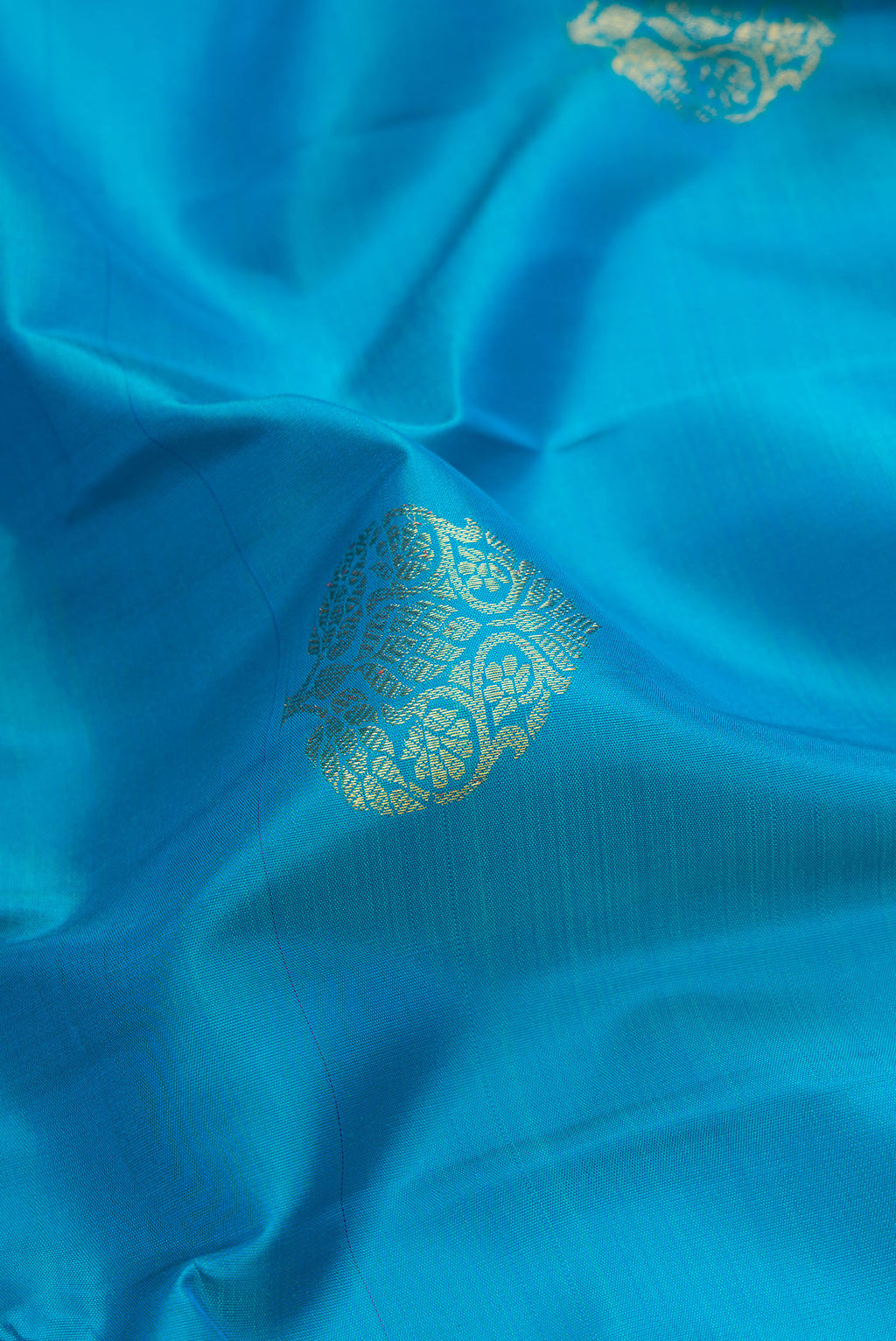 Close up of Sky Blue Dual Tone Kanjivaram Silk Saree with Zari Butta on the body and Zari Border.  displaying folds