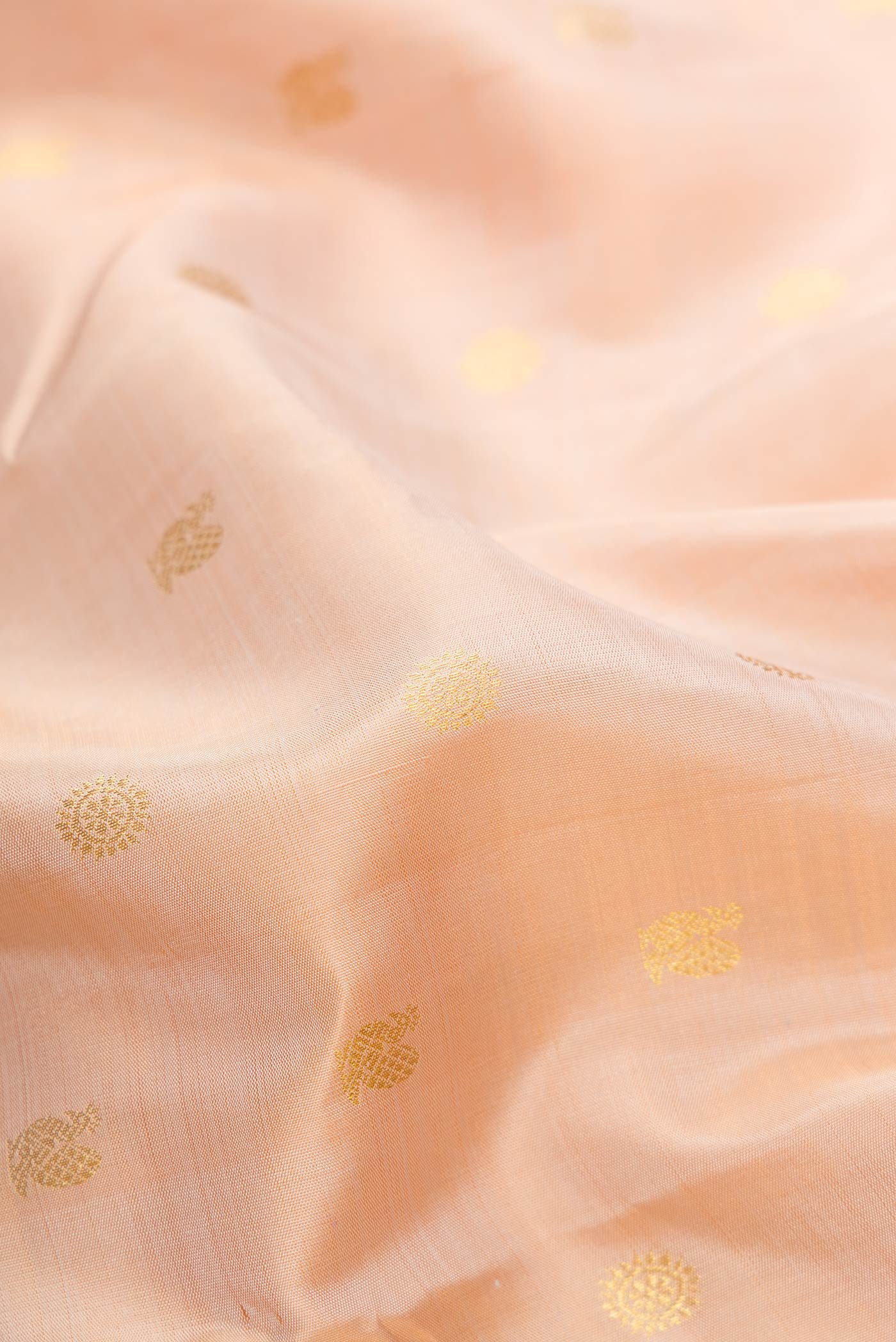 Close up of Rose Gold Dual Tone Kanjivaram Silk Saree with Zari Butta on the body and Zari Border.  displaying folds