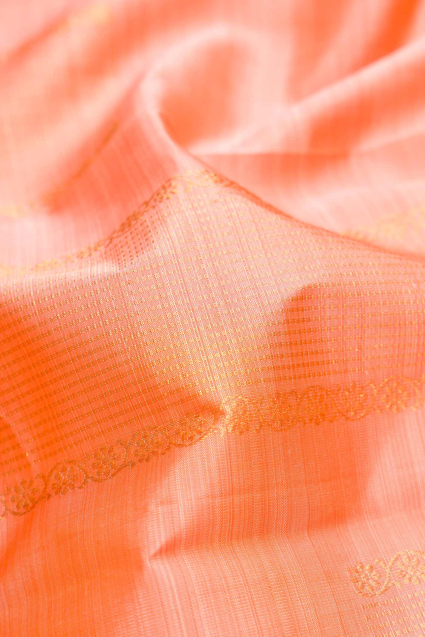 Close up of Peach Dual Tone Kanjivaram Silk Saree with Zari Butta on the body and Without Border.  displaying folds