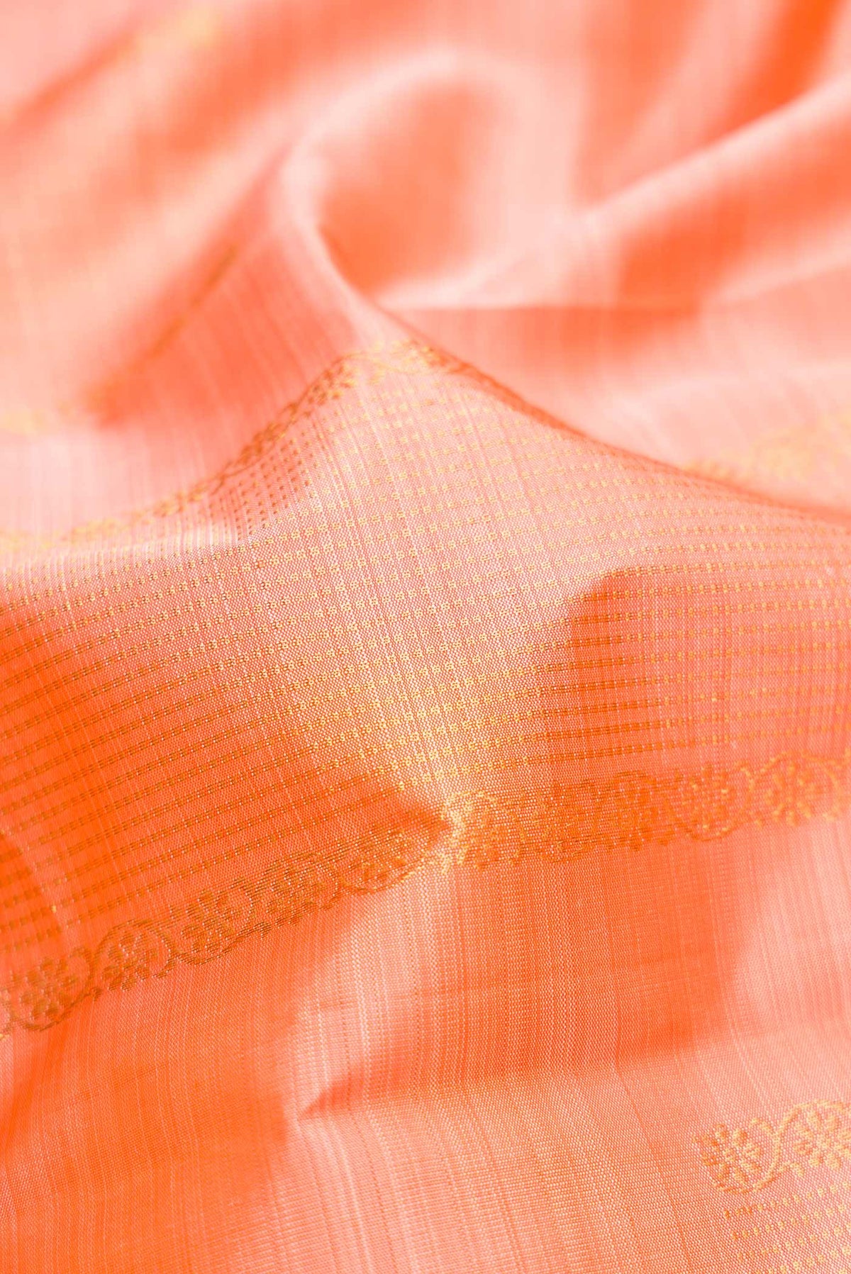 Close up of Peach Dual Tone Kanjivaram Silk Saree with Zari Butta on the body and Without Border.  displaying folds