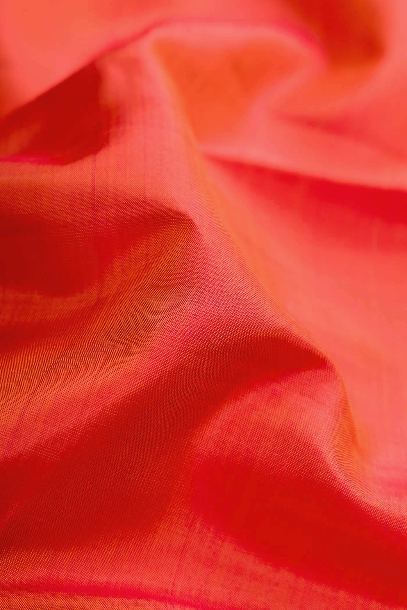 Close up of Orange Dual Tone Kanjivaram Silk Saree with Plain Body and Zari Border.  displaying folds